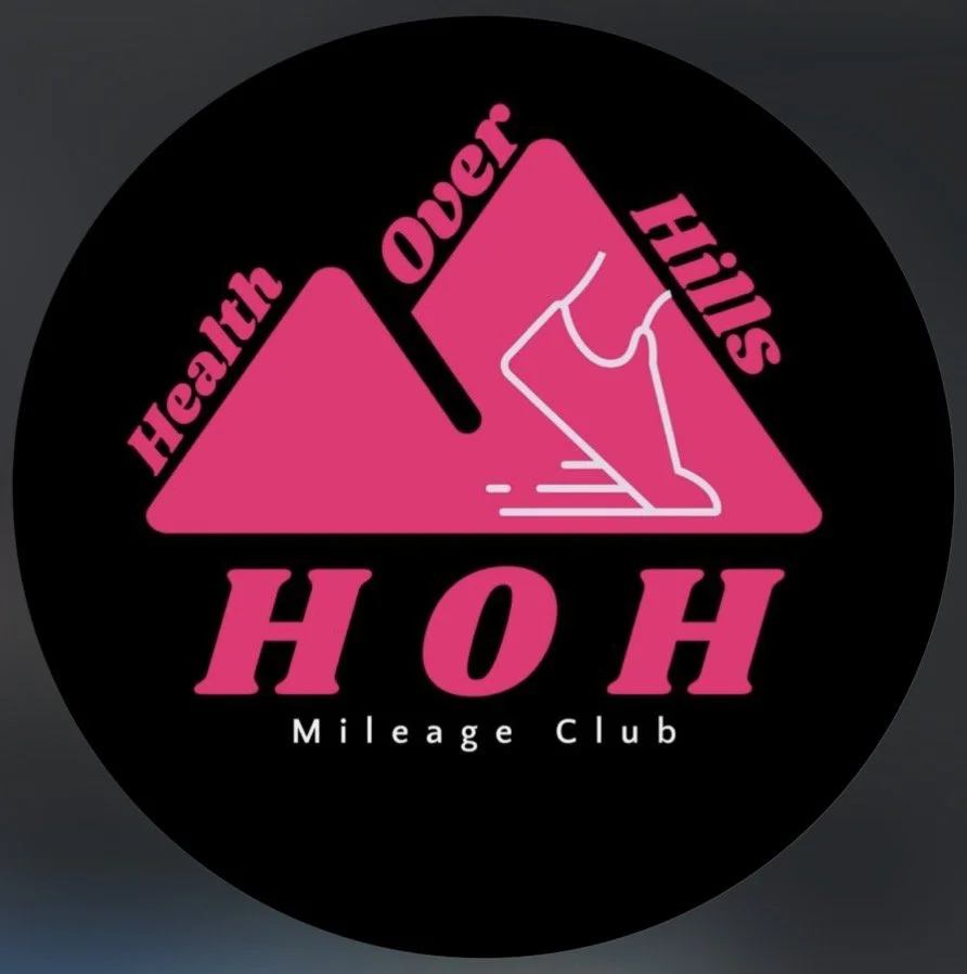 A black circular logo with pink mountains, a white outline of a shoe, and the words 'Health', 'Ouer', and 'Hills' in pink. The text 'HOH Mileage Club' is written at the bottom.