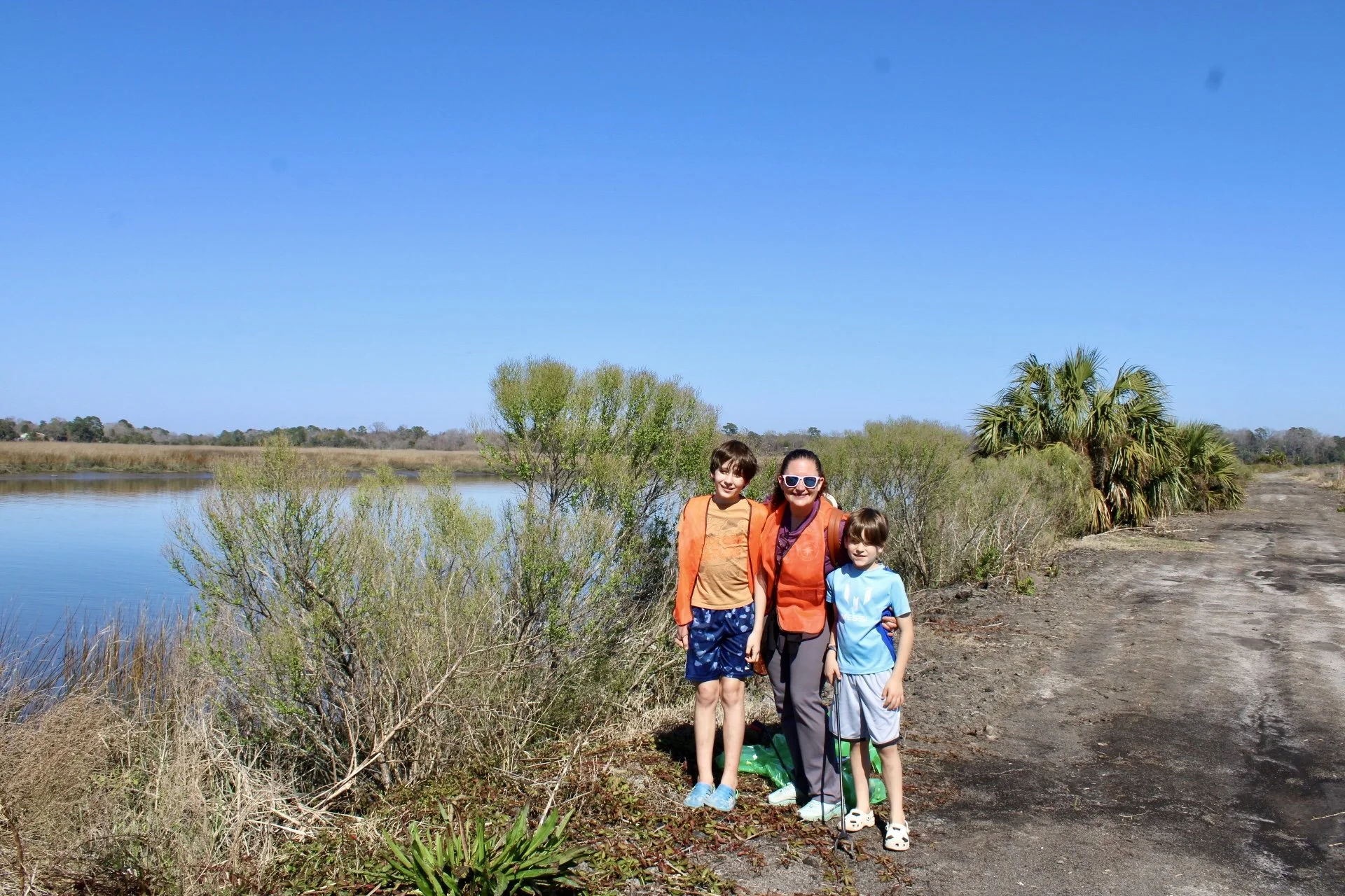 A mom and her two young boys stand on the shore in front of the Ashley River