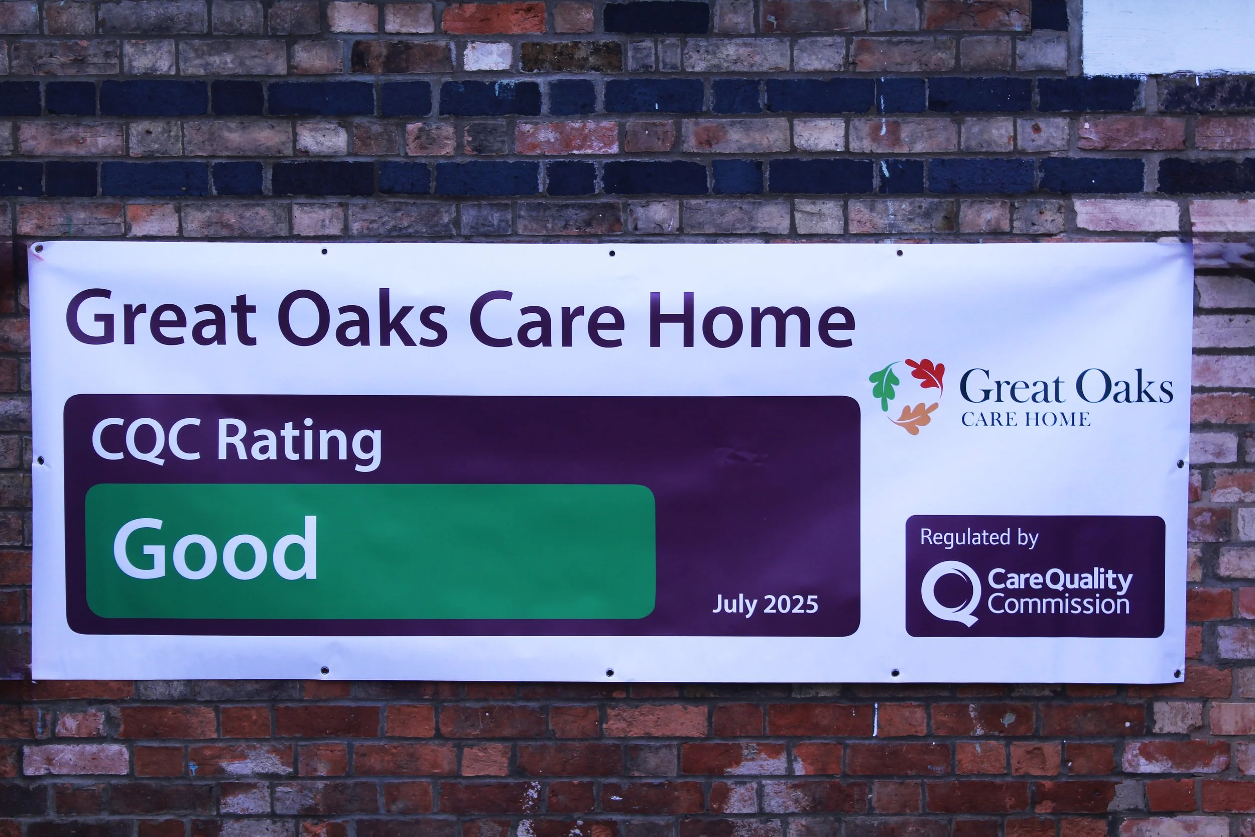 Banner on brick wall for Great Oaks Care Home displaying a CQC rating of 'Good', regulated by Care Quality Commission, dated July 2025.