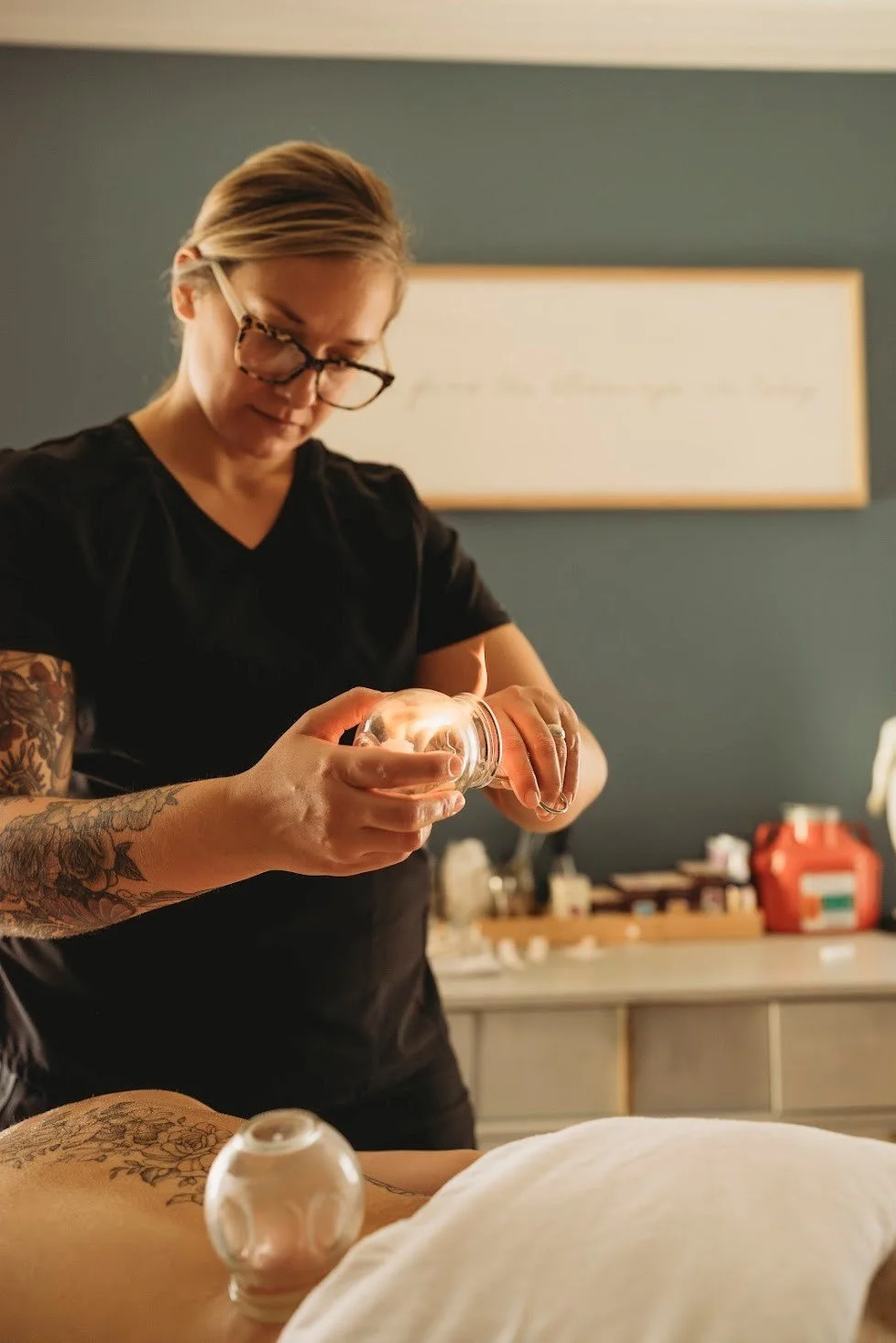 Dr. Samantha Burris lighting a traditional glass cupping cup for a patient at Essence Healing Acupuncture in Corning NY