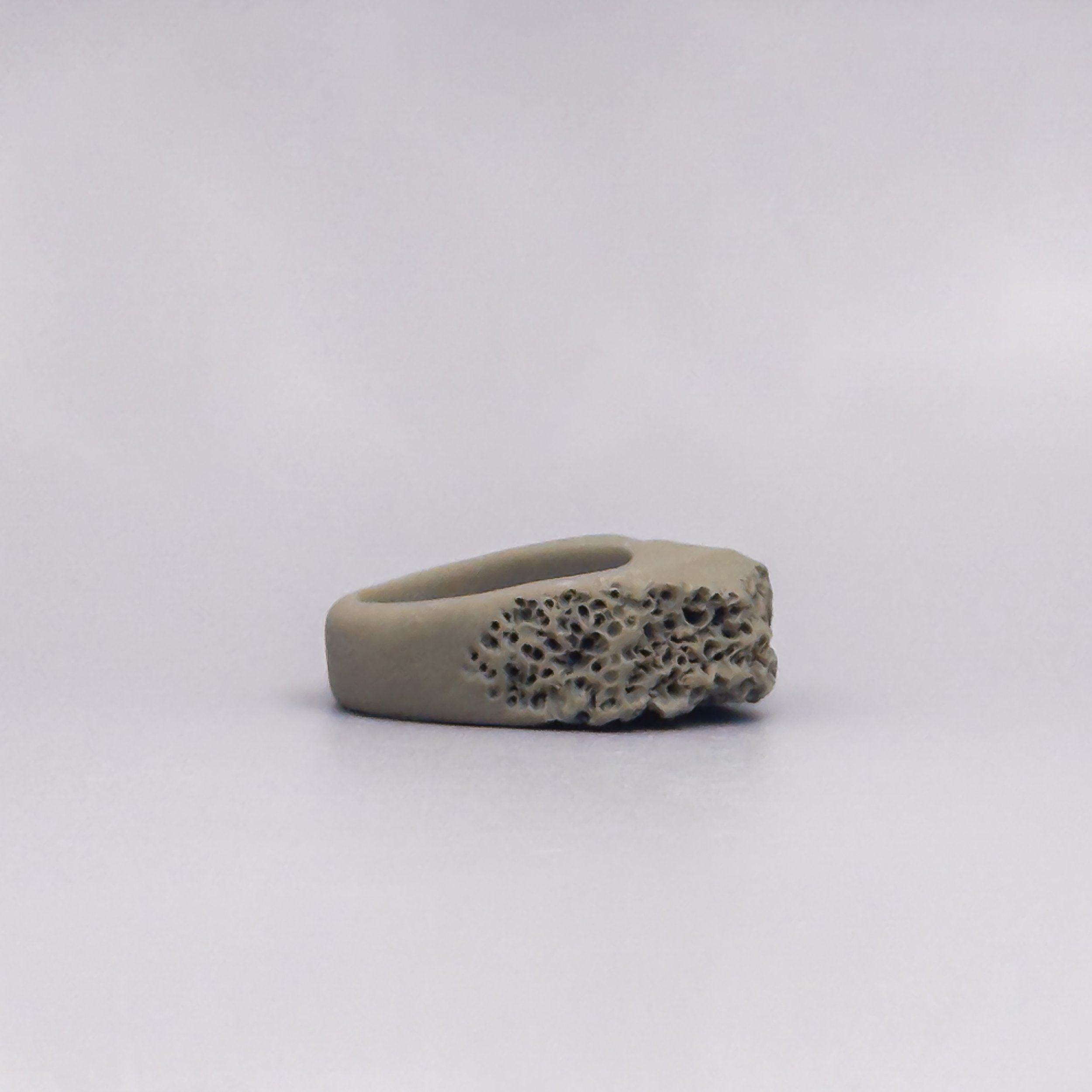 Unglazed ceramic ring with geometric body and fossil-like matte surface in natural clay finish