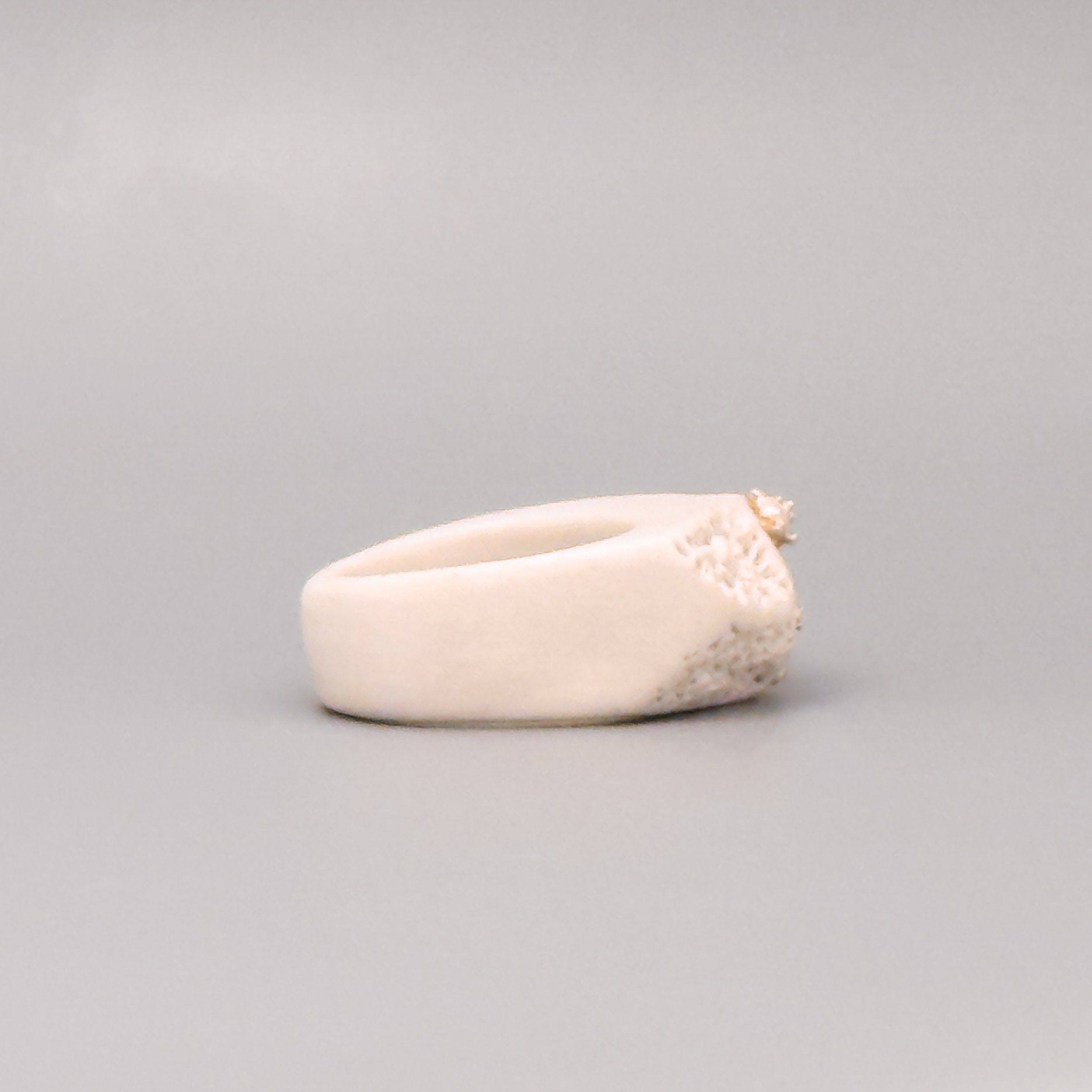 Side view of a white porcelain coral ring with textured crown and fused silver grains, handmade in Brooklyn