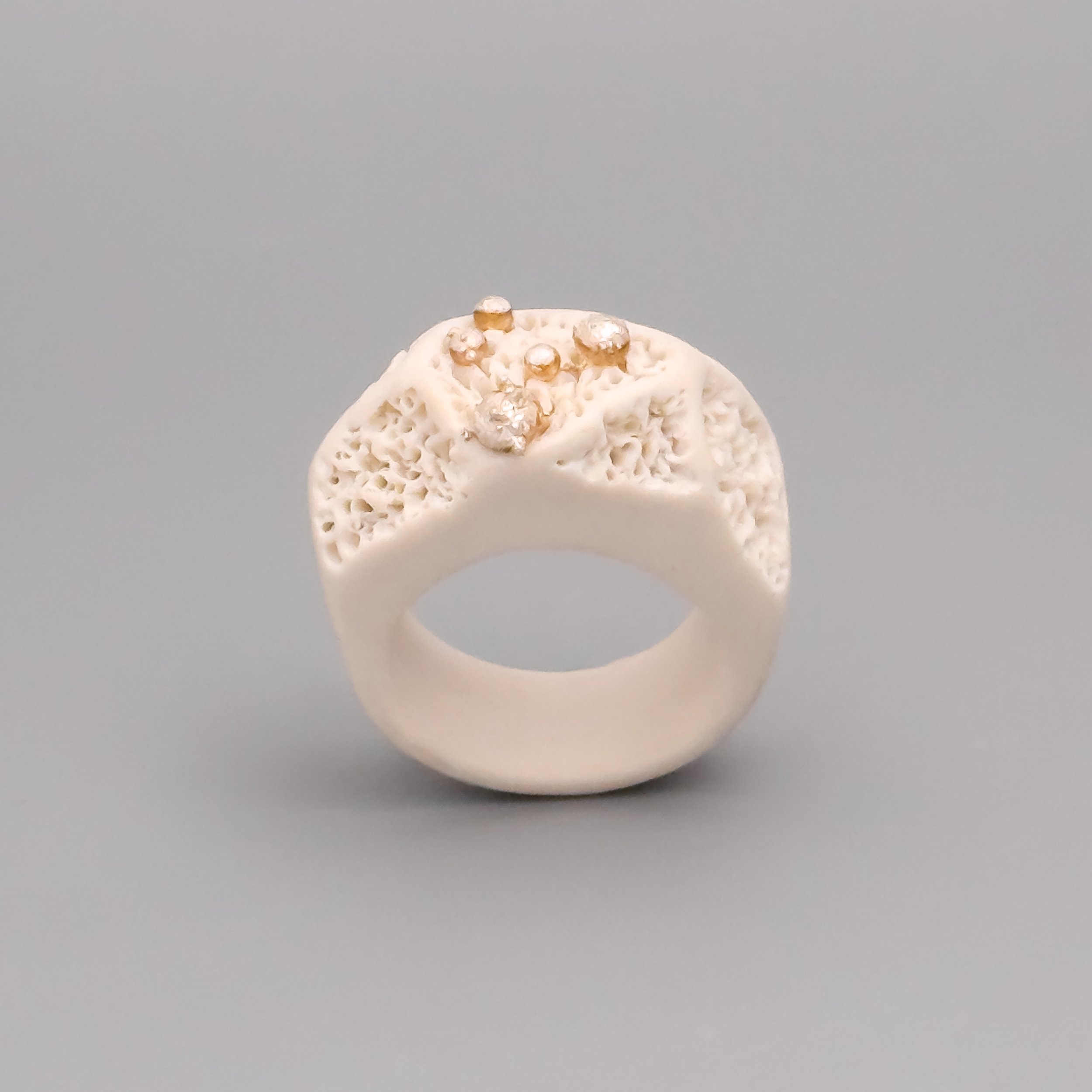 Angled view of sculptural white ceramic ring with coral texture and silver accents, art jewelry made in New York
