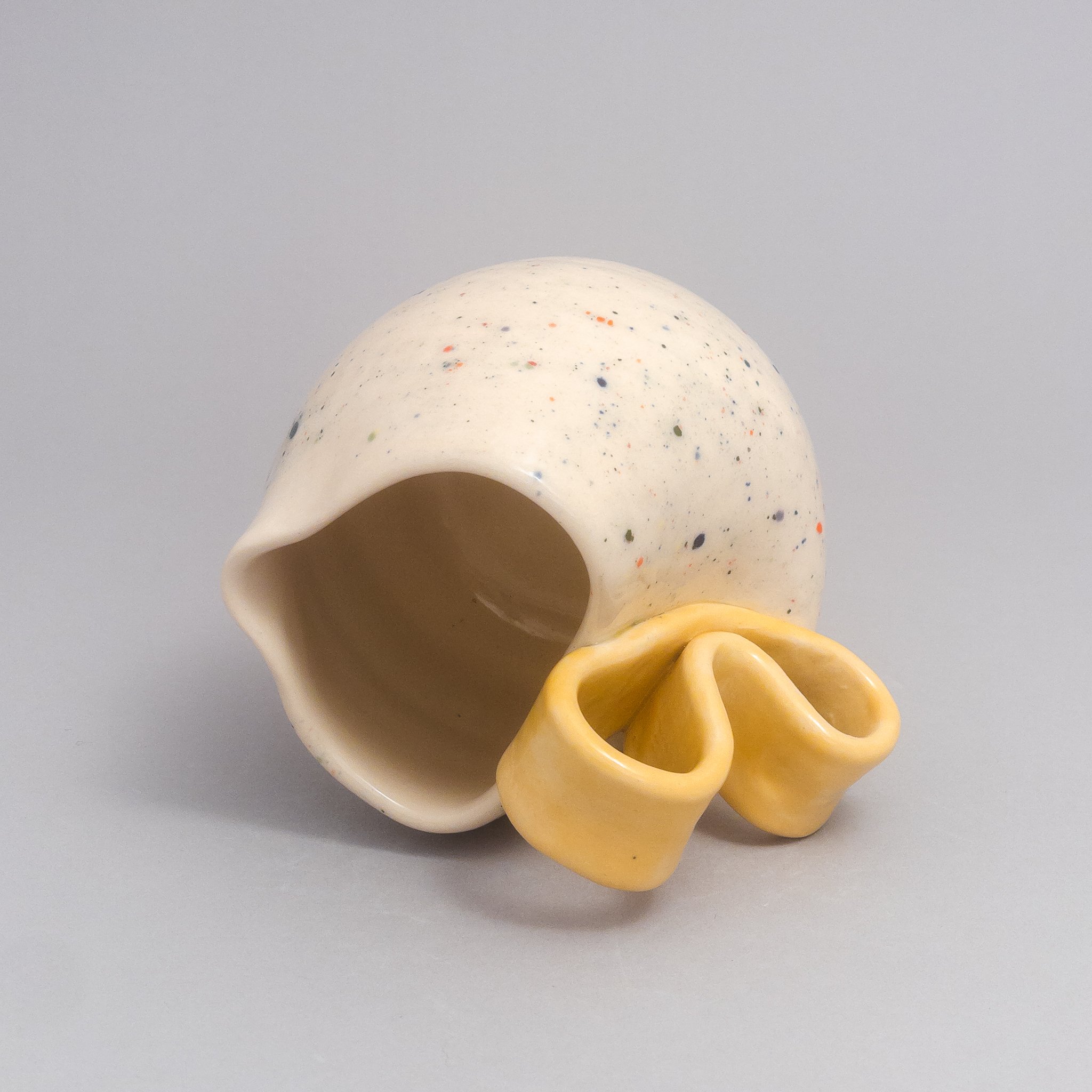 Speckled ceramic pitcher lying on its side, showing the glossy interior and sculptural handle by Argilla NYC