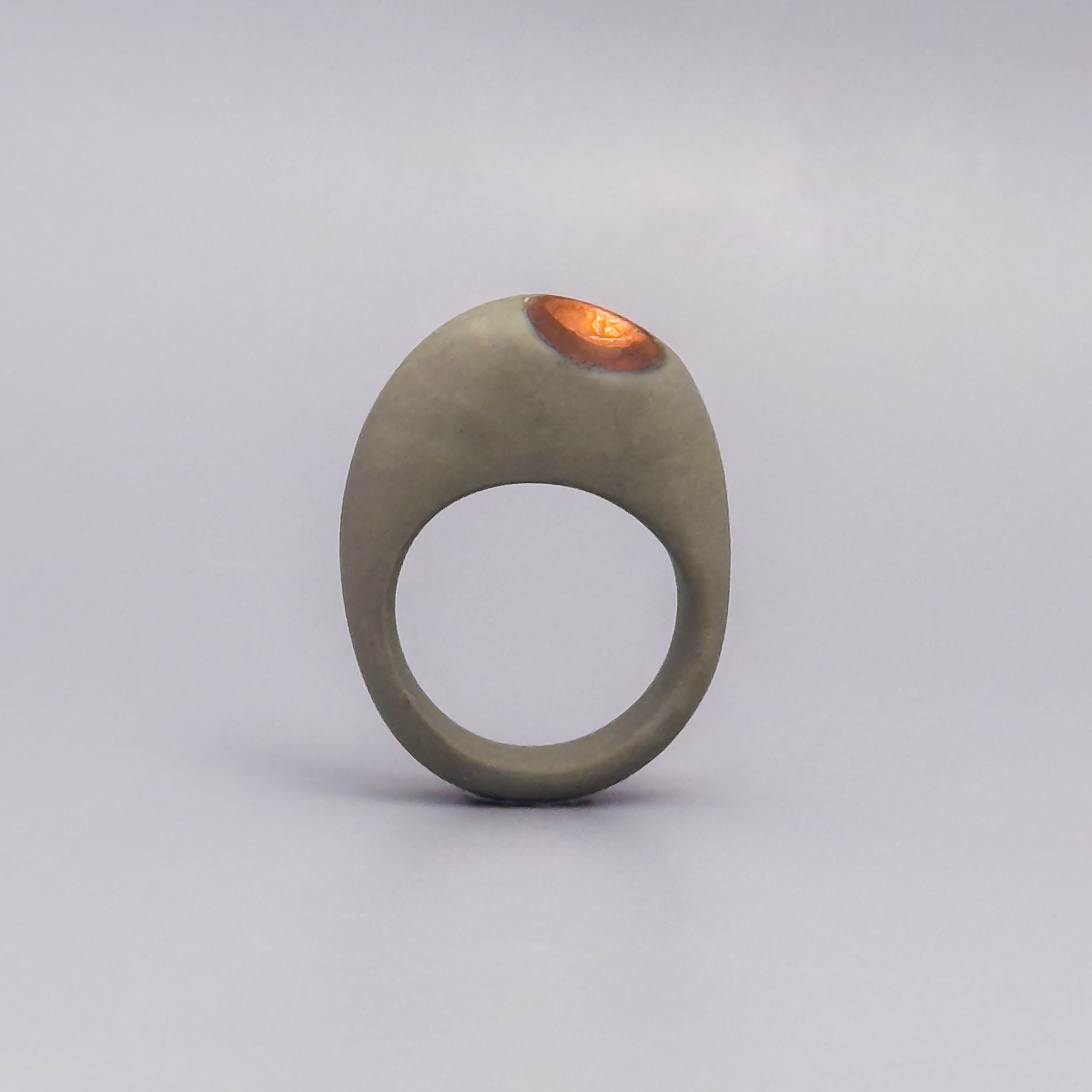 Sculptural ceramic ring in olive porcelain with off-center metallic copper hollow