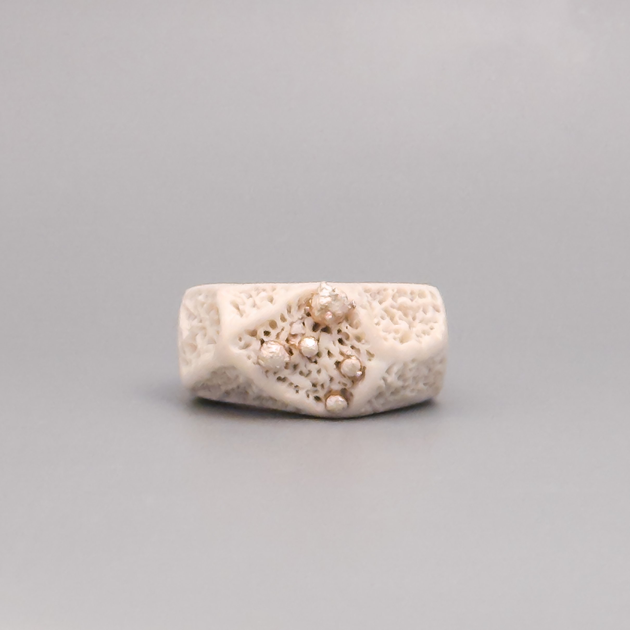 Front-facing ceramic ring showing sculptural coral texture and silver cluster detail on matte porcelain