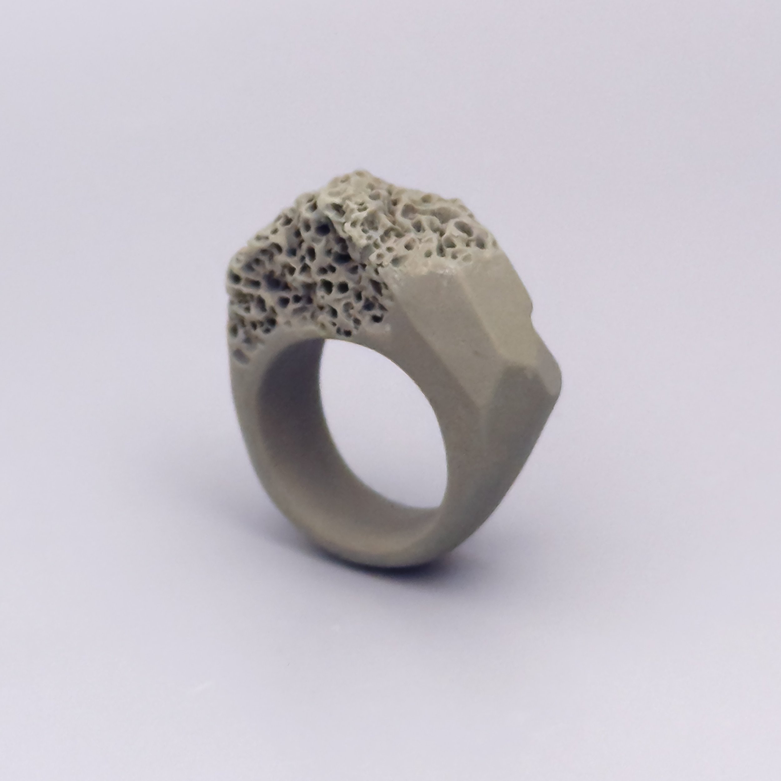 Sculptural ceramic ring in sand-toned porcelain with angular body and reef-like textured top