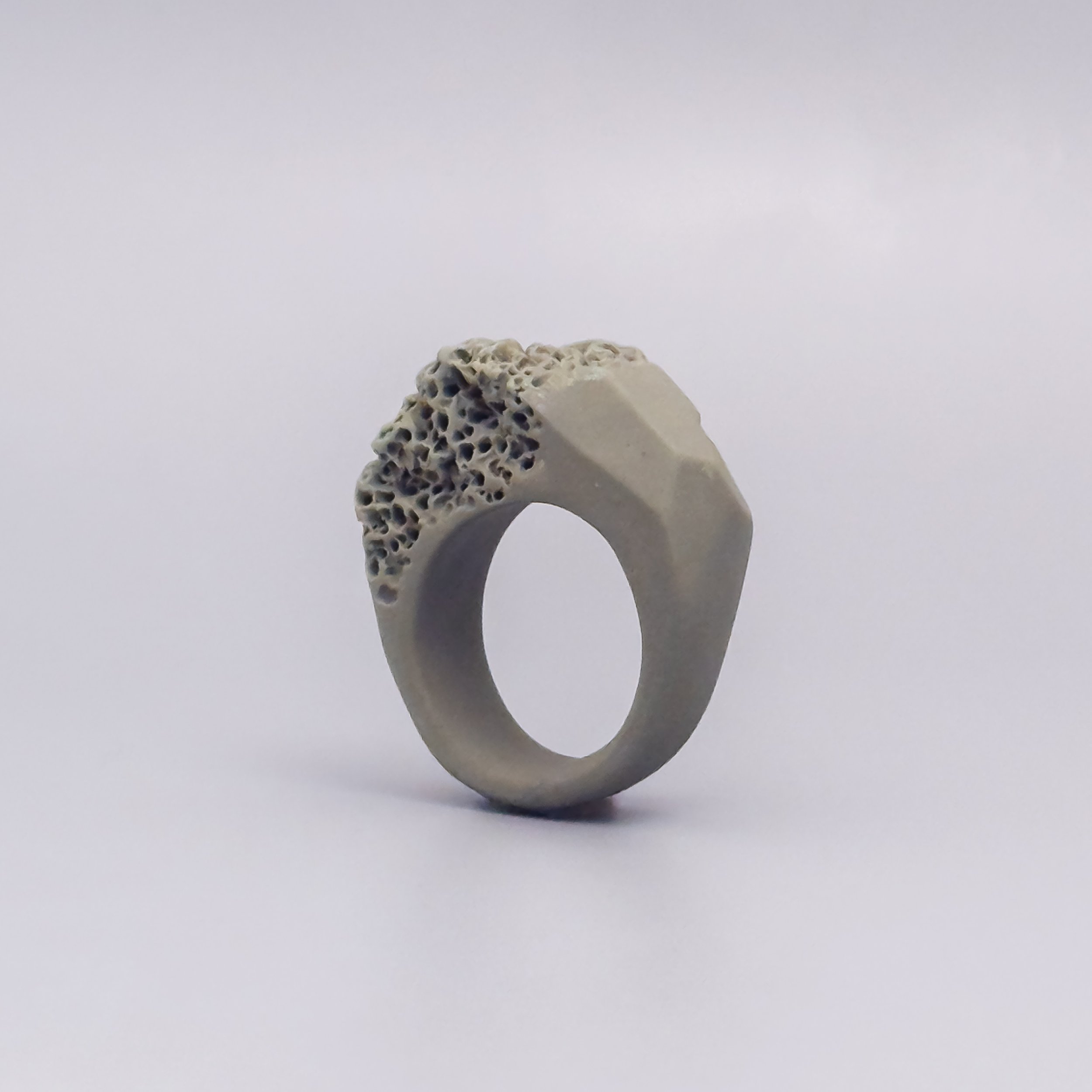 Sand-colored porcelain ring with faceted side and coral-textured crown, handmade from pigmented ceramic clay