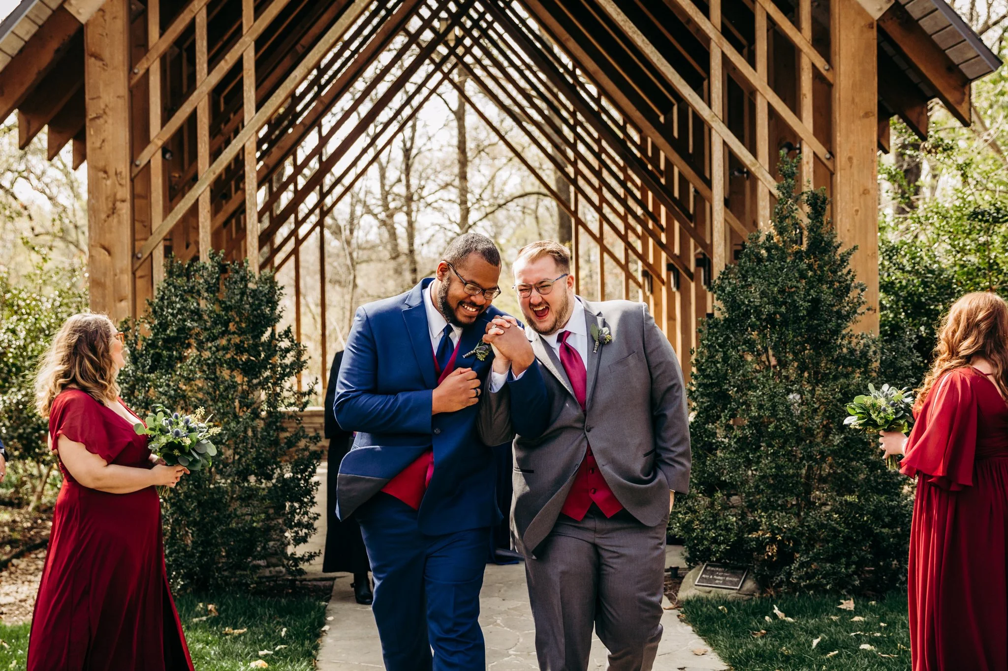 LGBTQ Memphis Botanic Garden Wedding. Two grooms hold hands and skip joyously