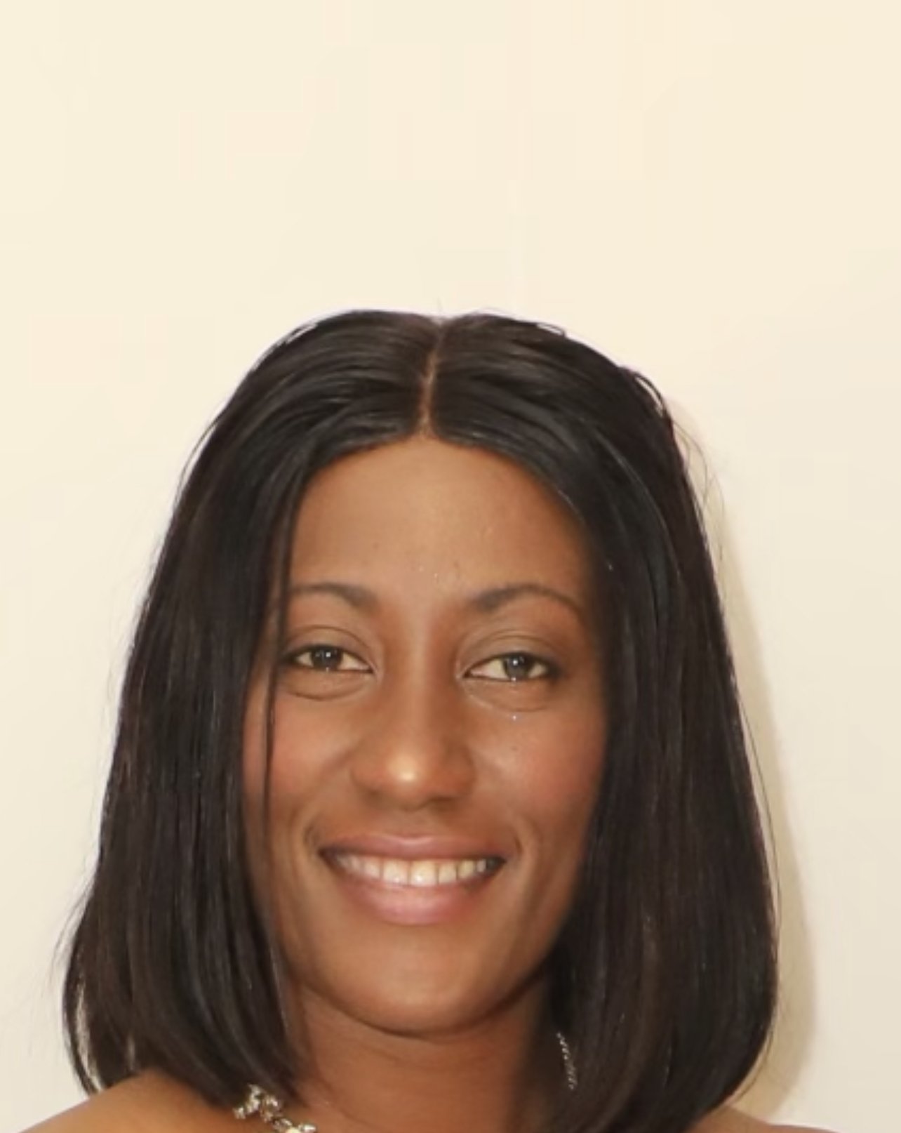 A woman with straight, shoulder-length black hair smiling in front of a plain light-colored background.