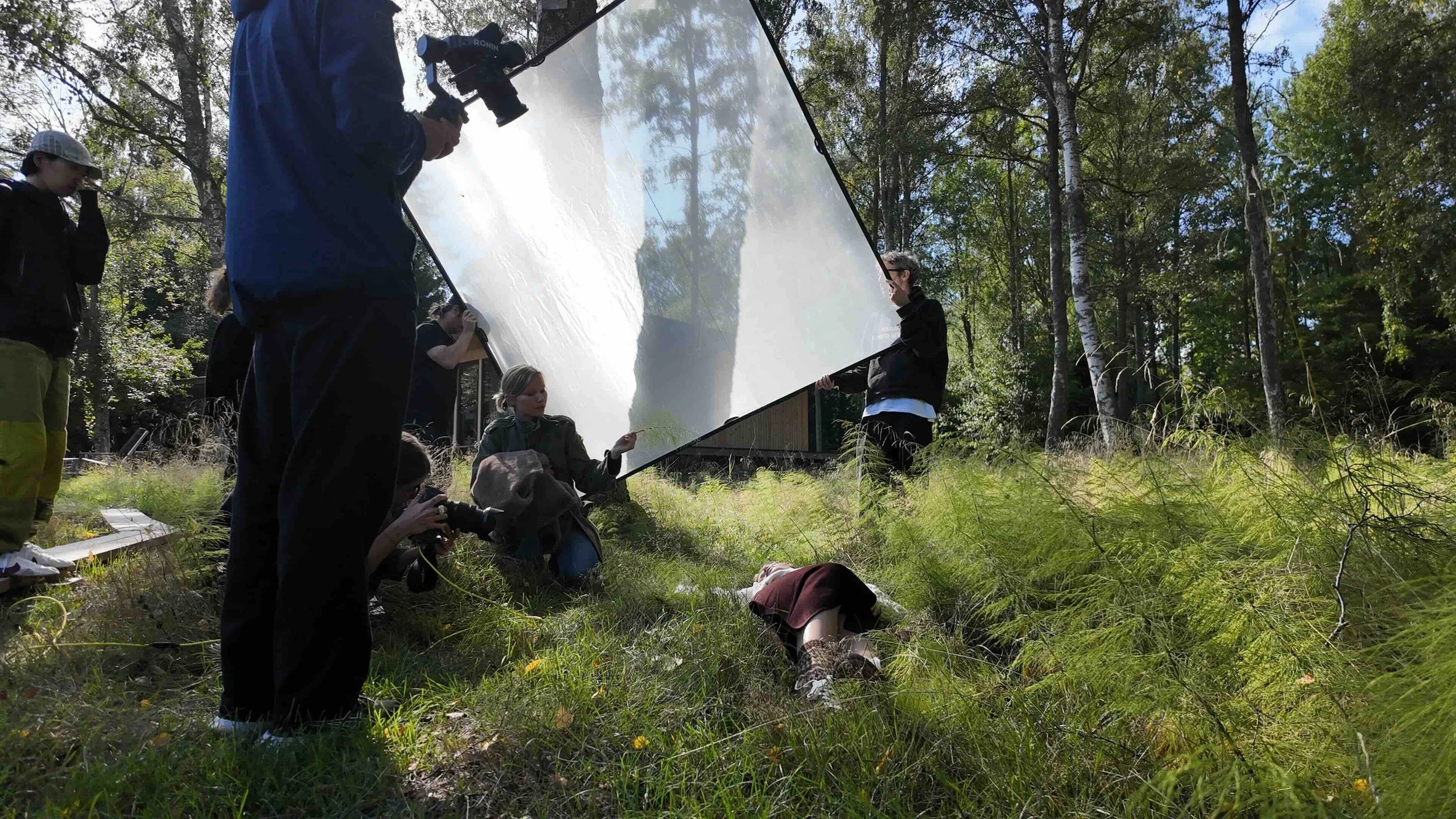 Film8 crew using a reflector to light a model during Fabrique's Autumn/Winter 2026 outdoor fashion shoot in Sweden.