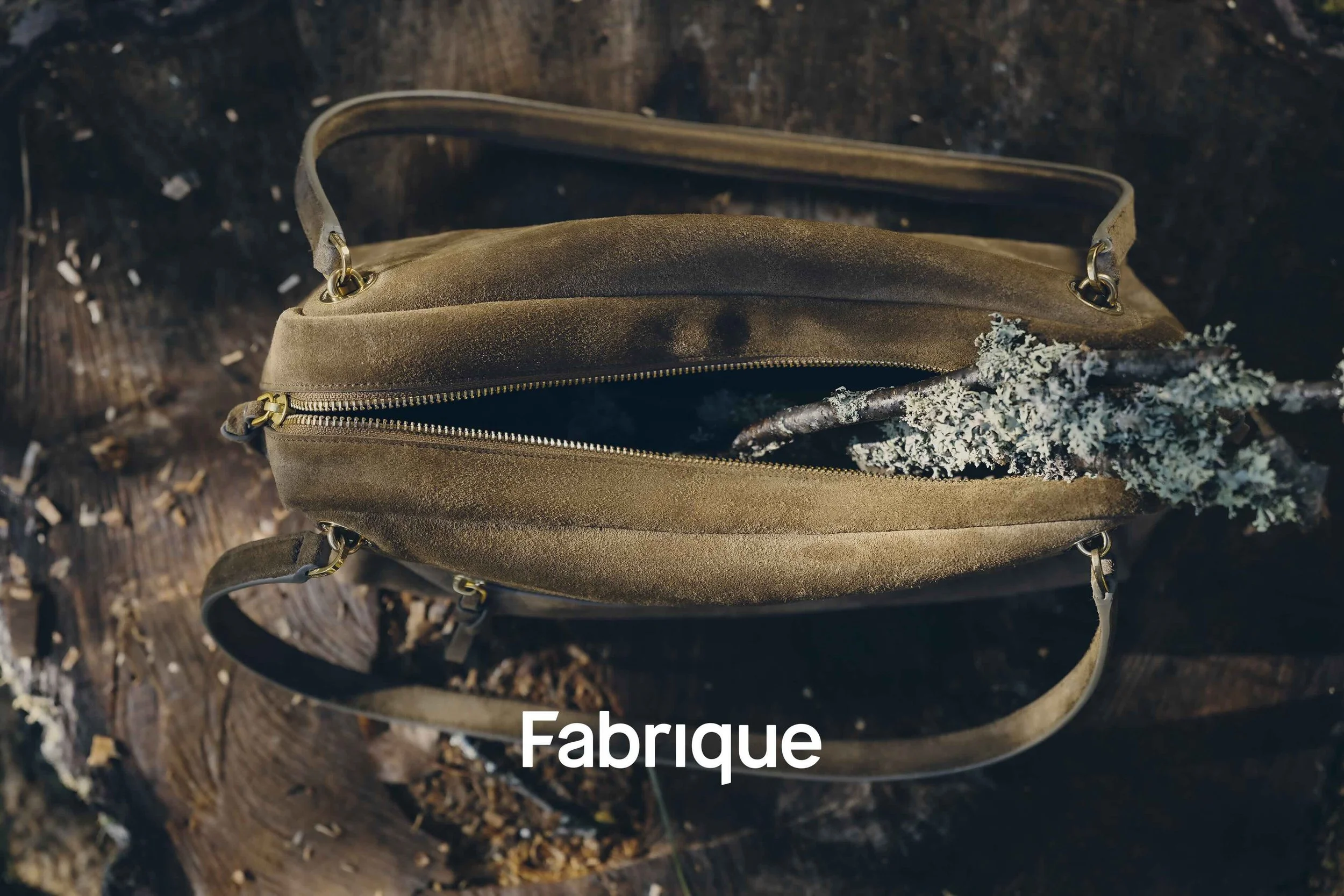 Närbild på en brun handväska i mocka från Fabriques höst-/vinterkollektion 2026, stylad med naturliga texturer för en modekampanj.