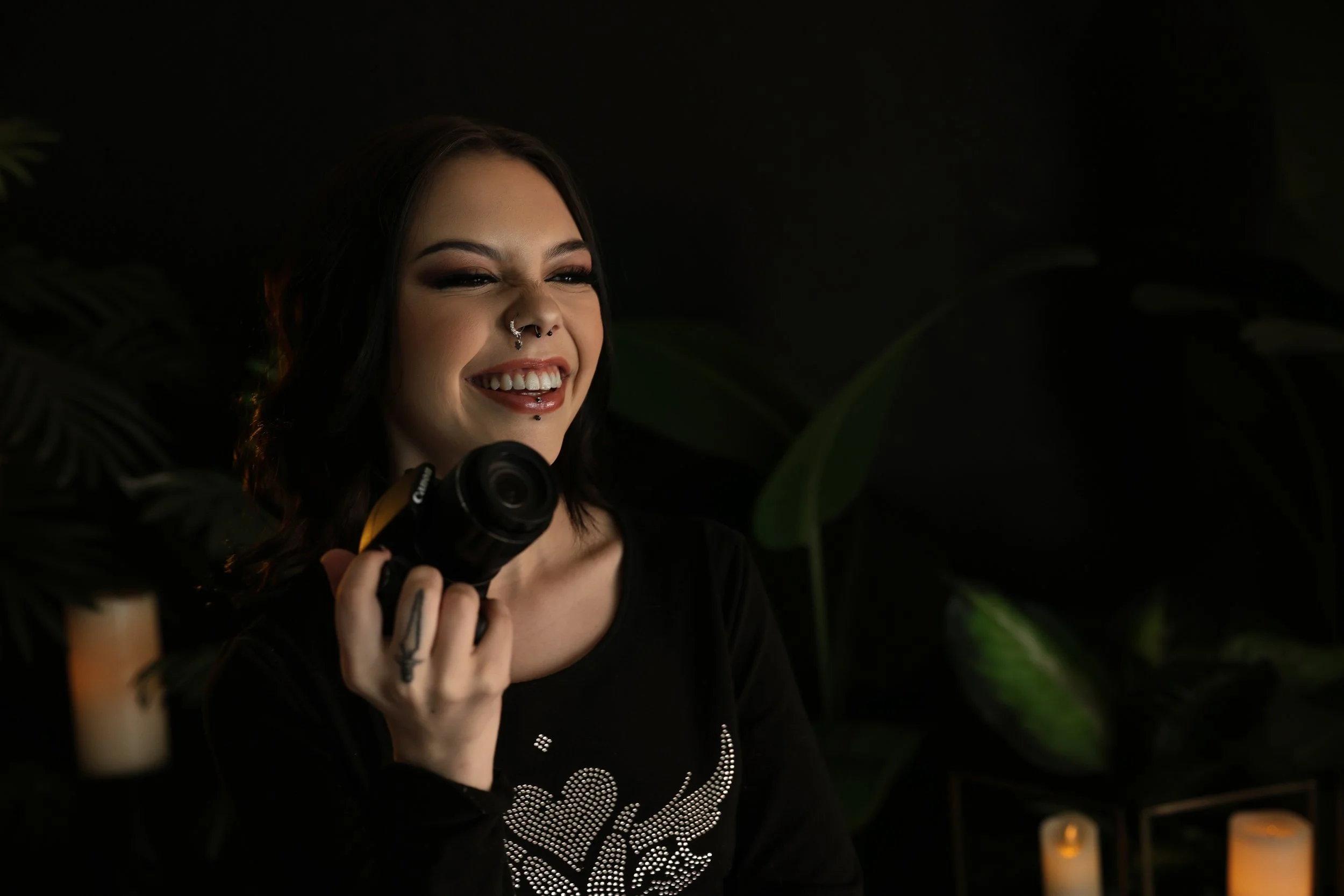 Laughing senior portrait with a dark, alternative style holding a camera in Phoenix