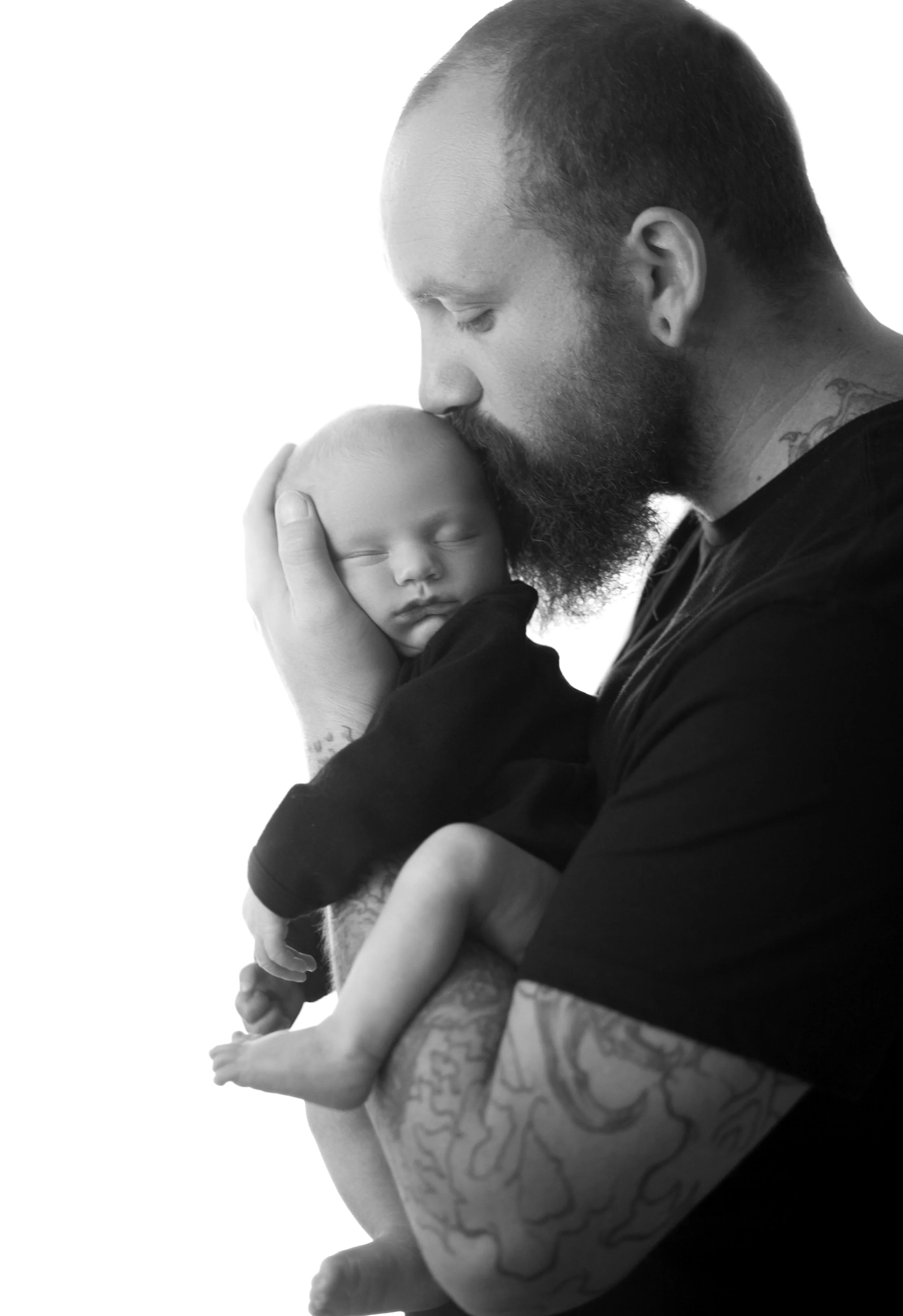 Tender moment of a dad kissing his newborn baby on the head in a Phoenix newborn session