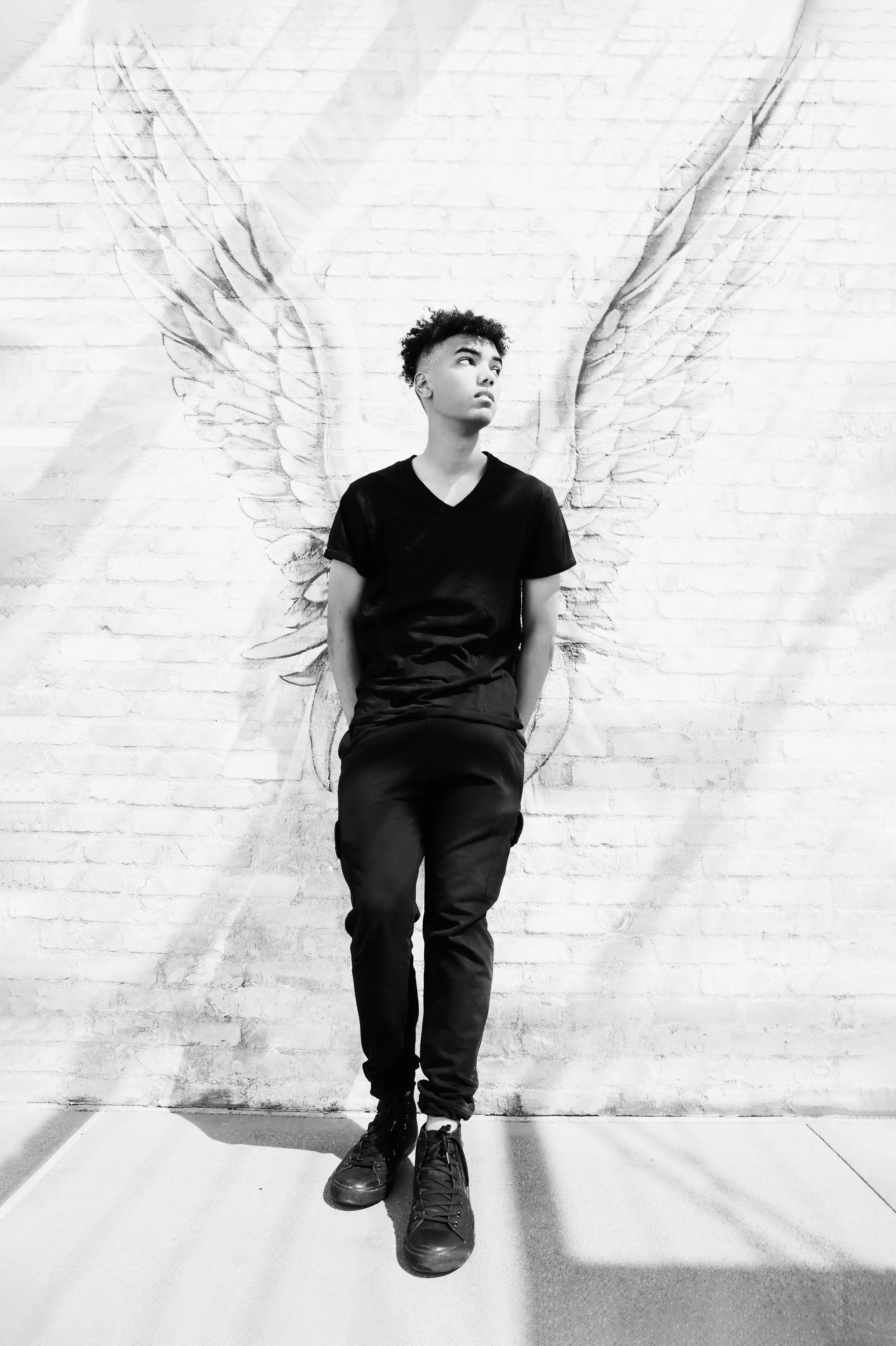 Senior photo of a male student posing against a mural with wings in Phoenix