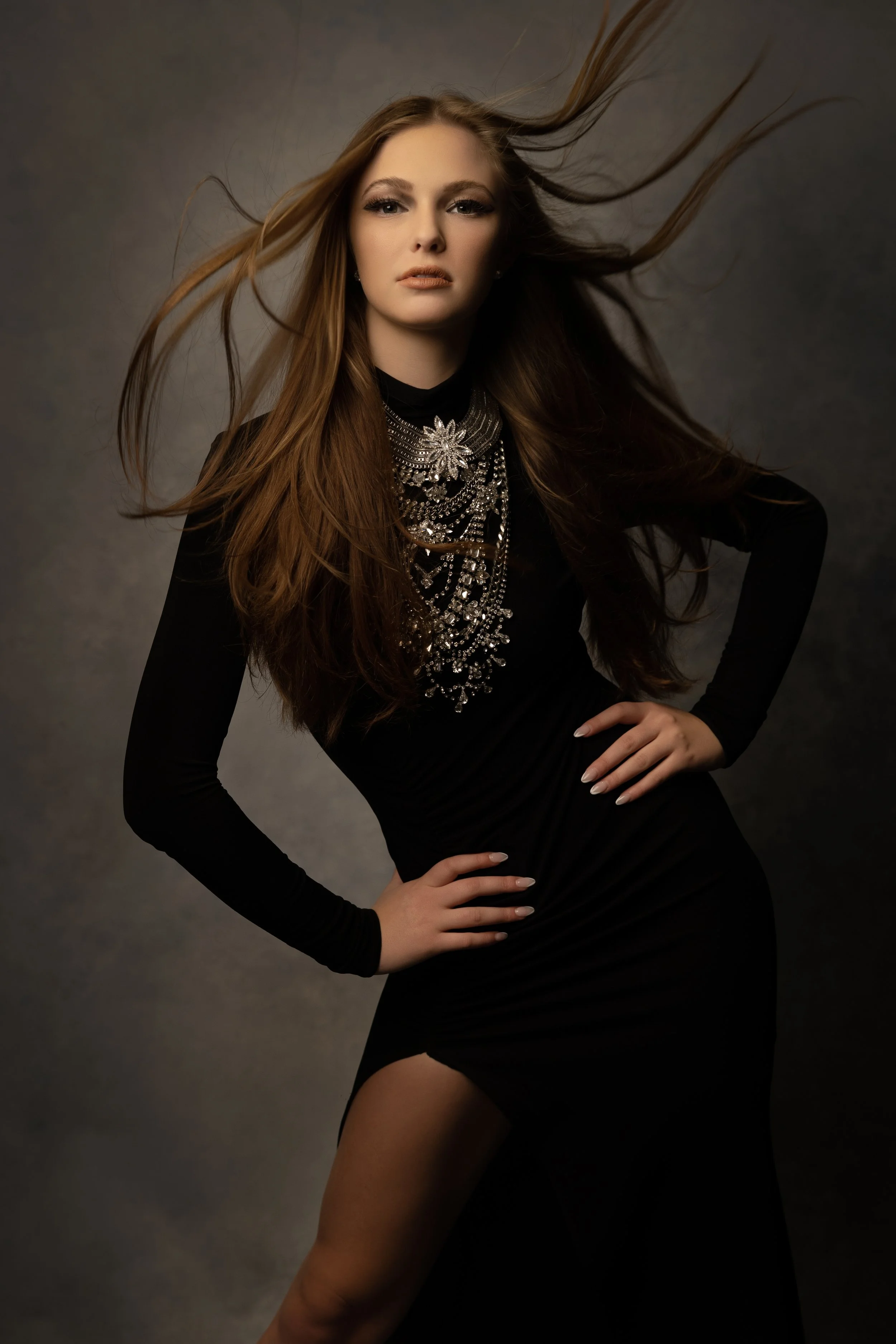 Fine art portrait of a young woman with flowing hair in a black dress against a gray backdrop in Phoenix