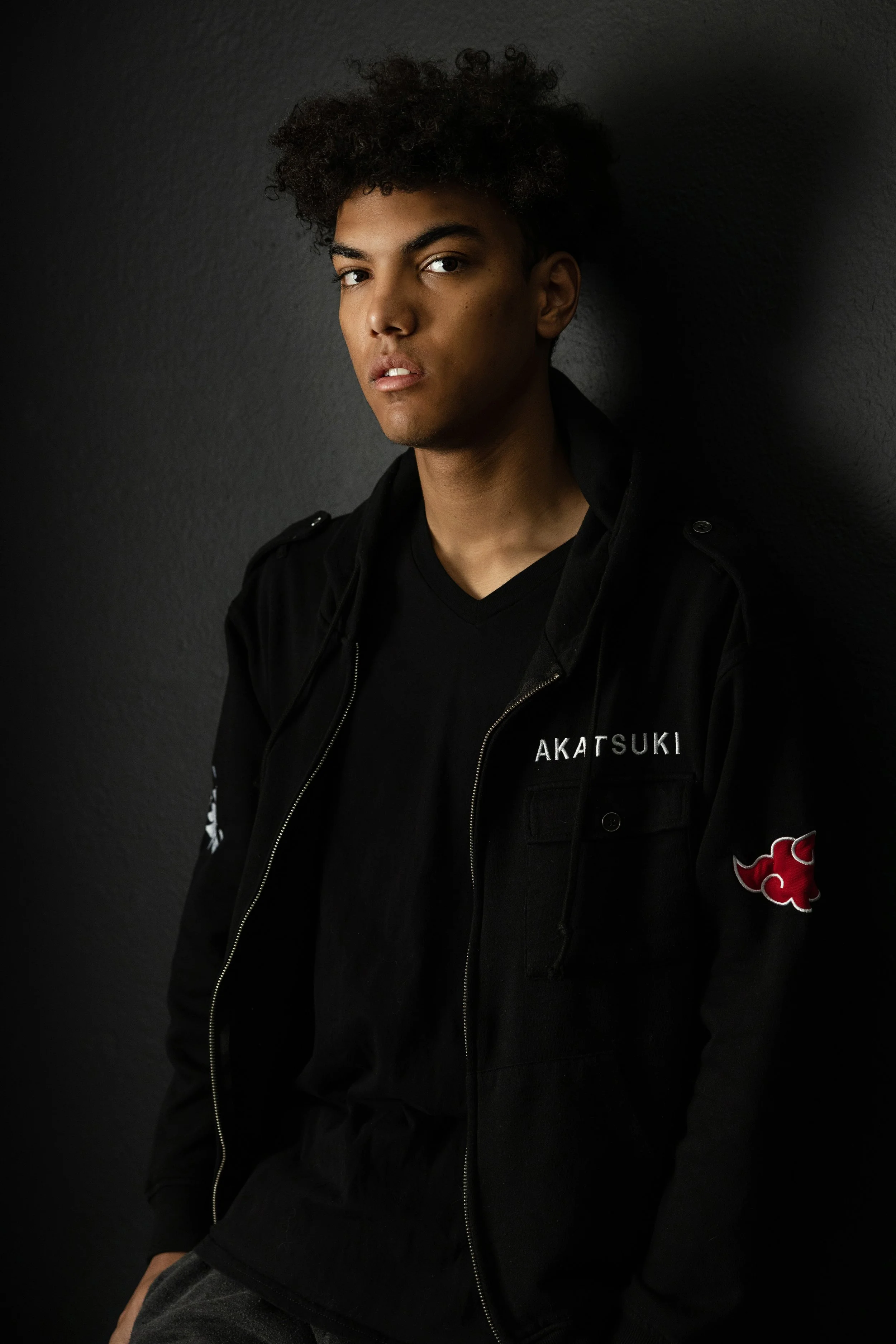 High school senior with an afro and anime-inspired fashion in a moody studio portrait in Phoenix