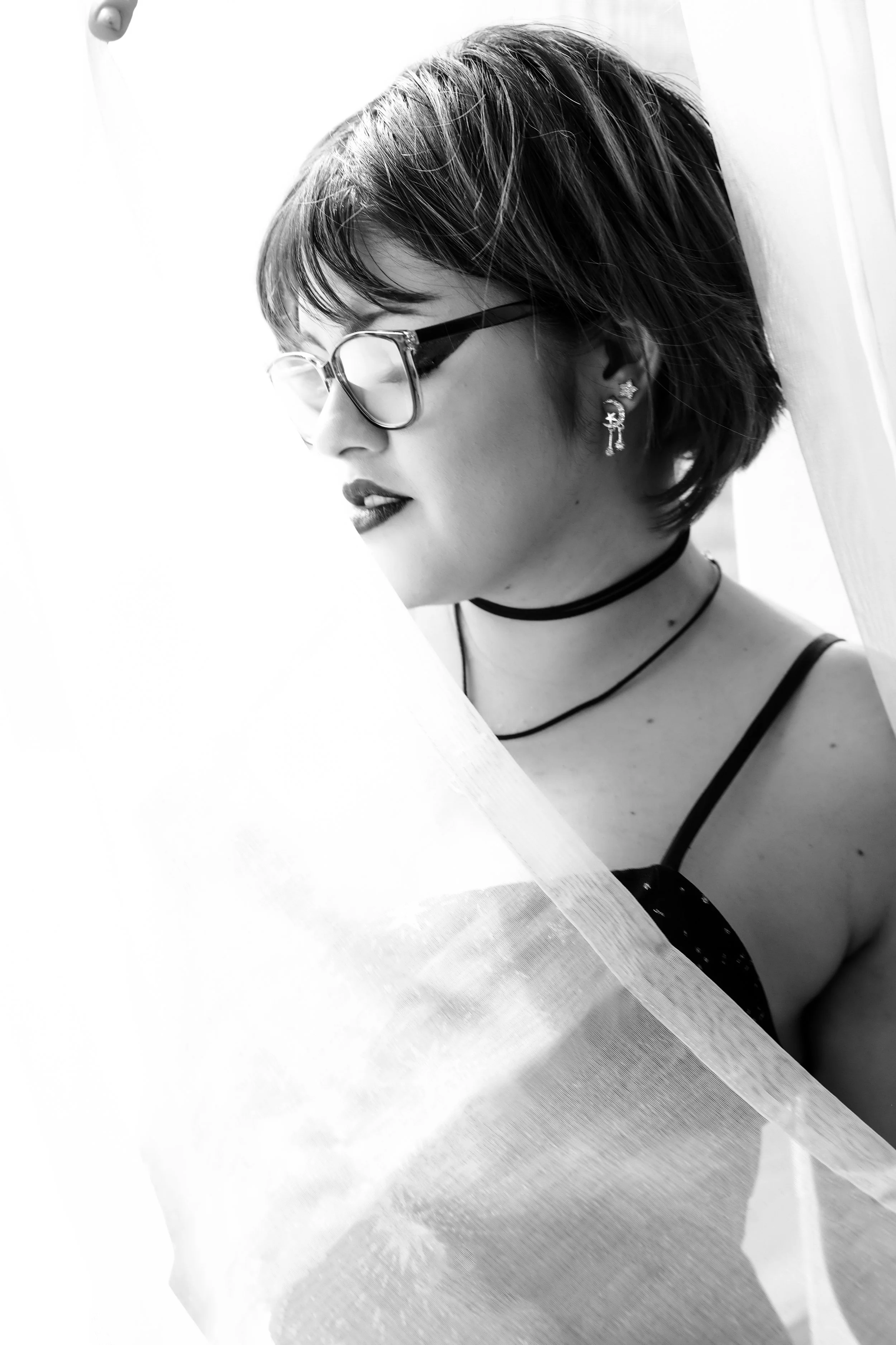 Alternative-style senior portrait with glasses and soft window lighting in Phoenix