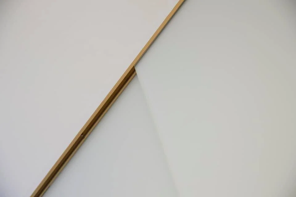 Close-up of a minimalist desk with a white surface and a wooden edge.