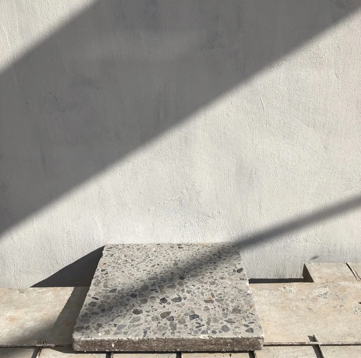 Concrete steps next to a white wall with shadows cast across the surface.