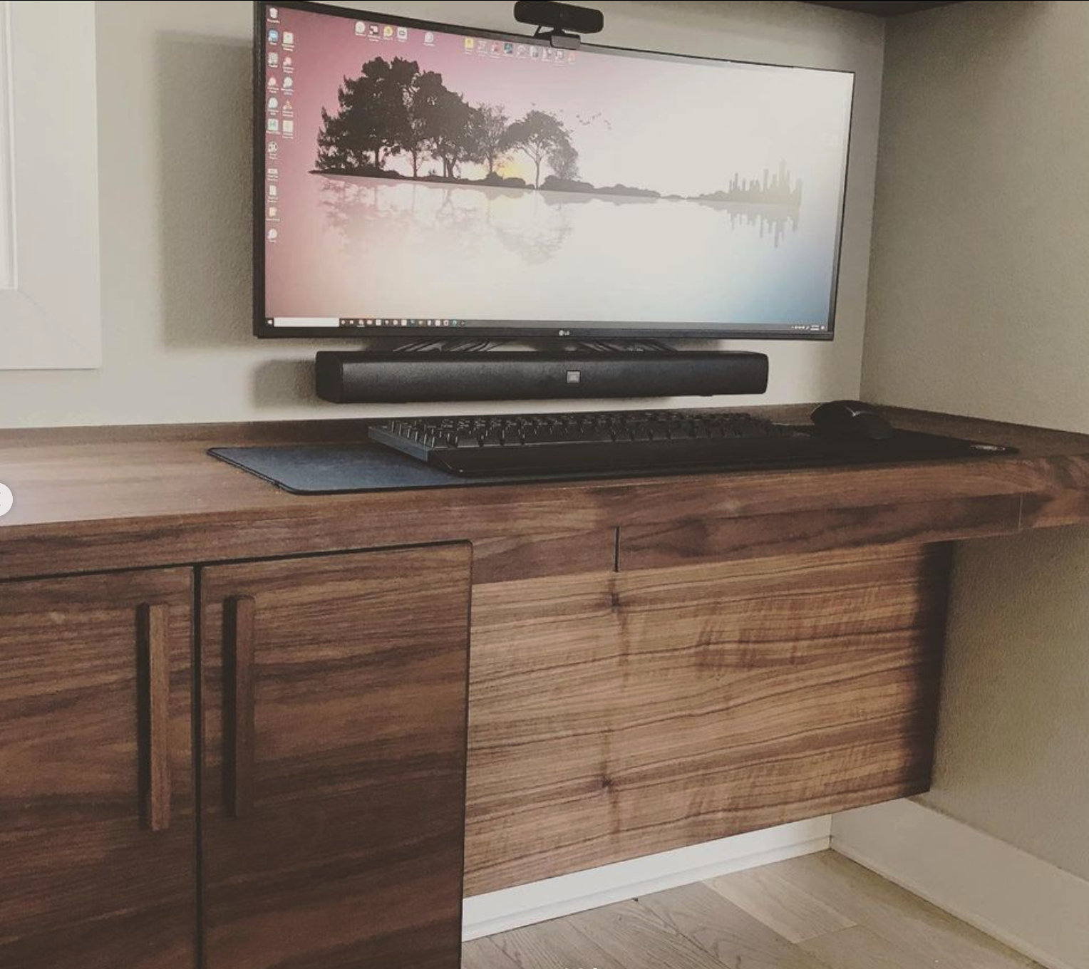 Floating walnut desk with hidden computer and cable routing.