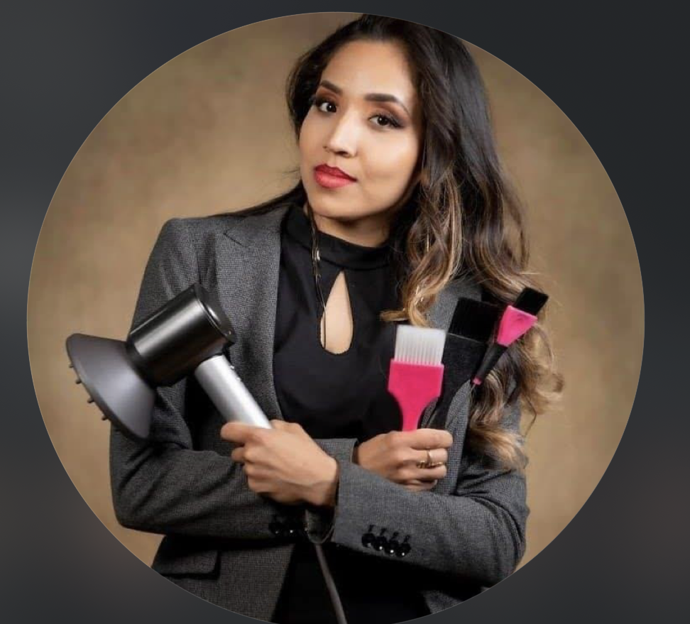 A woman in a business suit holding a hairdryer and three hairbrushes.