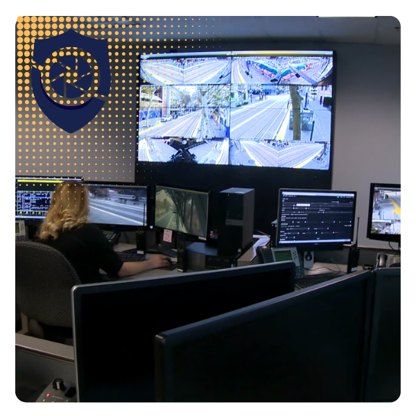 Security control room with multiple monitors displaying security footage of streets and intersections, a person working at a desk, and a shield icon with a clock on a dotted yellow background.