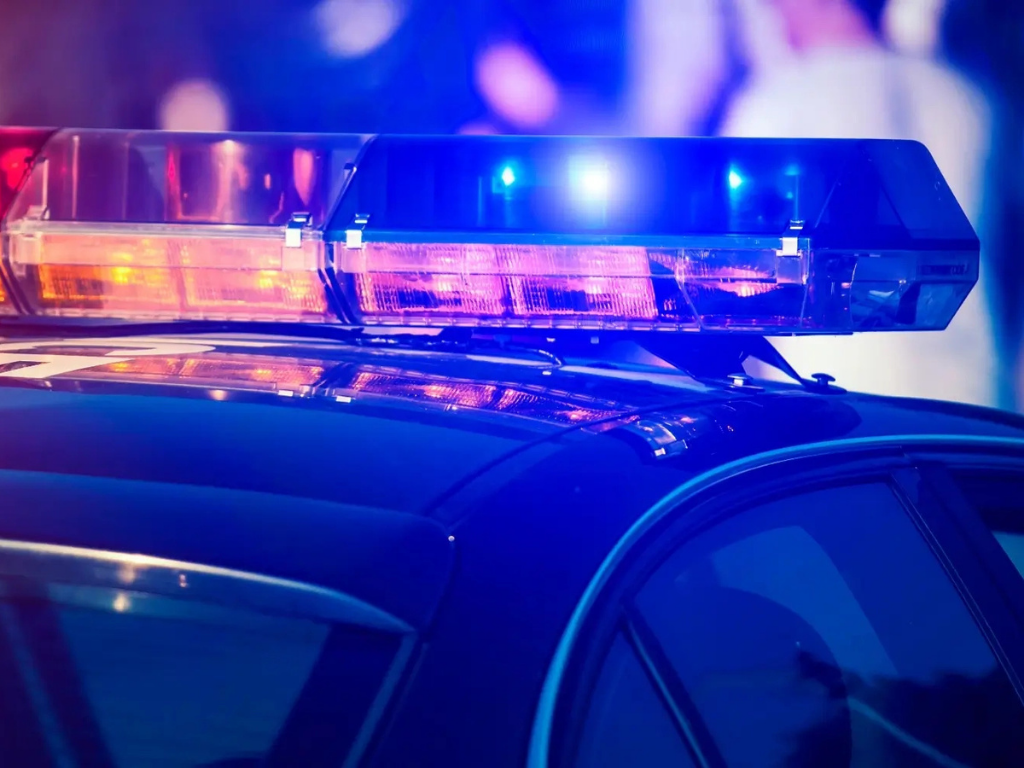 Police car with flashing blue and red emergency lights on its roof.