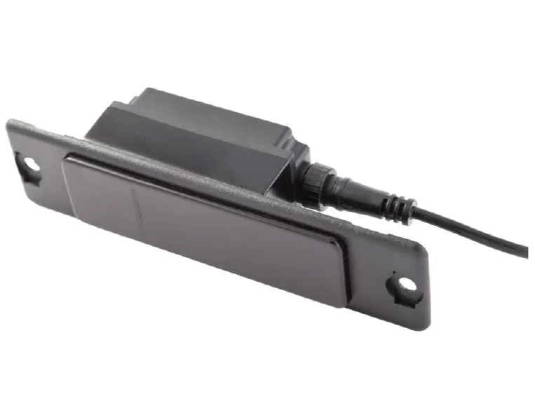 A black electronic sensor with a wiring cord attached, mounted on a metal plate with mounting holes.