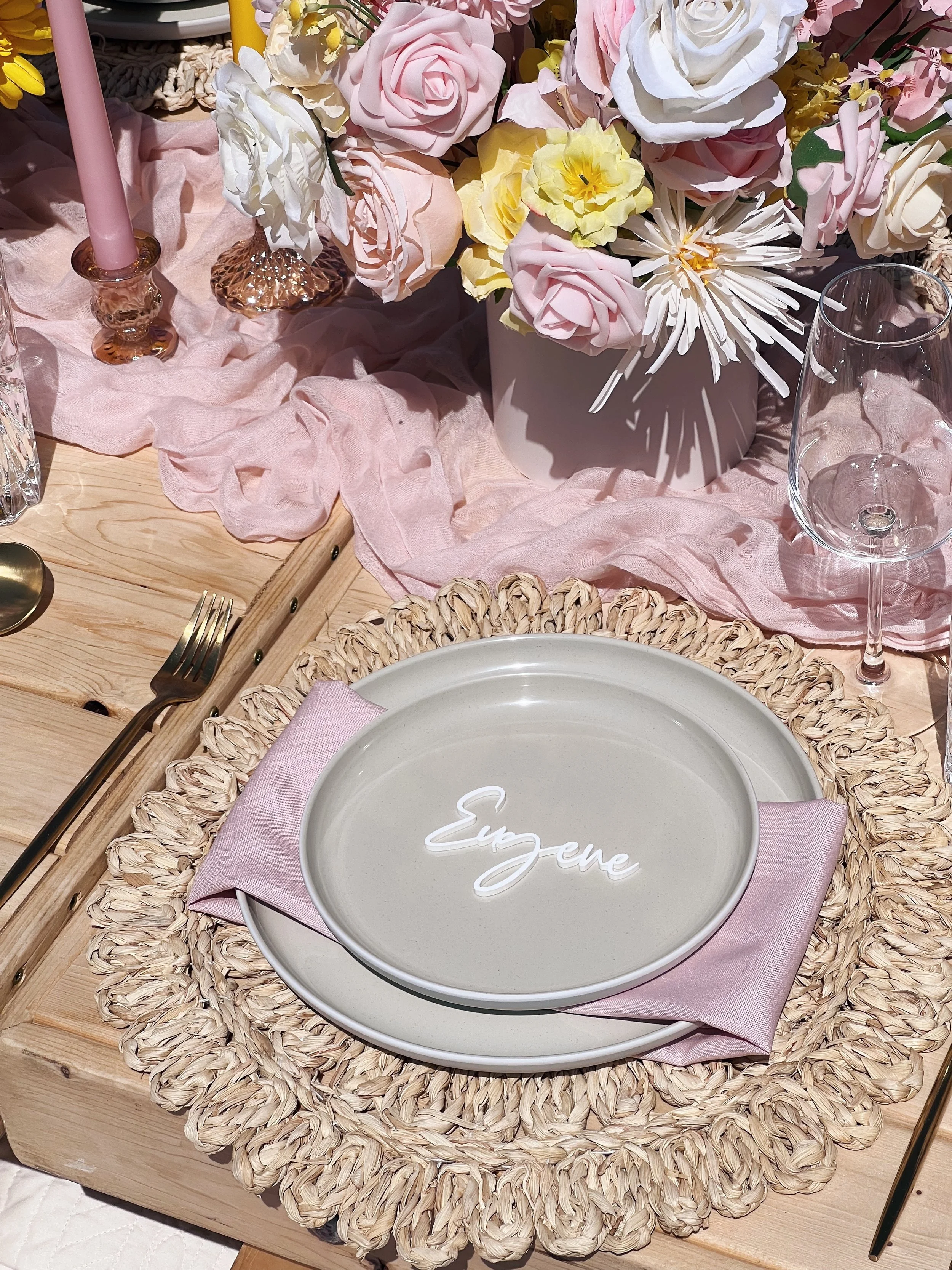 Mrs personalized name card laying on a napkin with a peacock feather at a picnic table dining set designed by Picnics By Peace