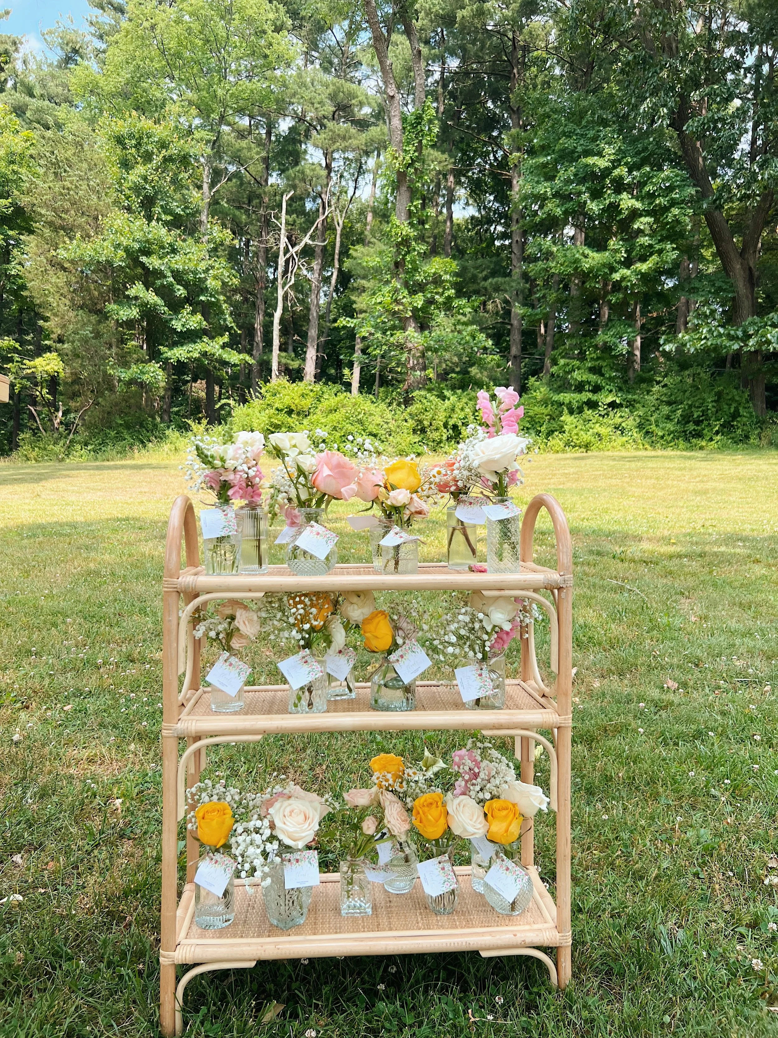 Rattan shelf holding a customizable wooden sign sitting by a picnic basket and indoor picnic set out by Picnics By Peace