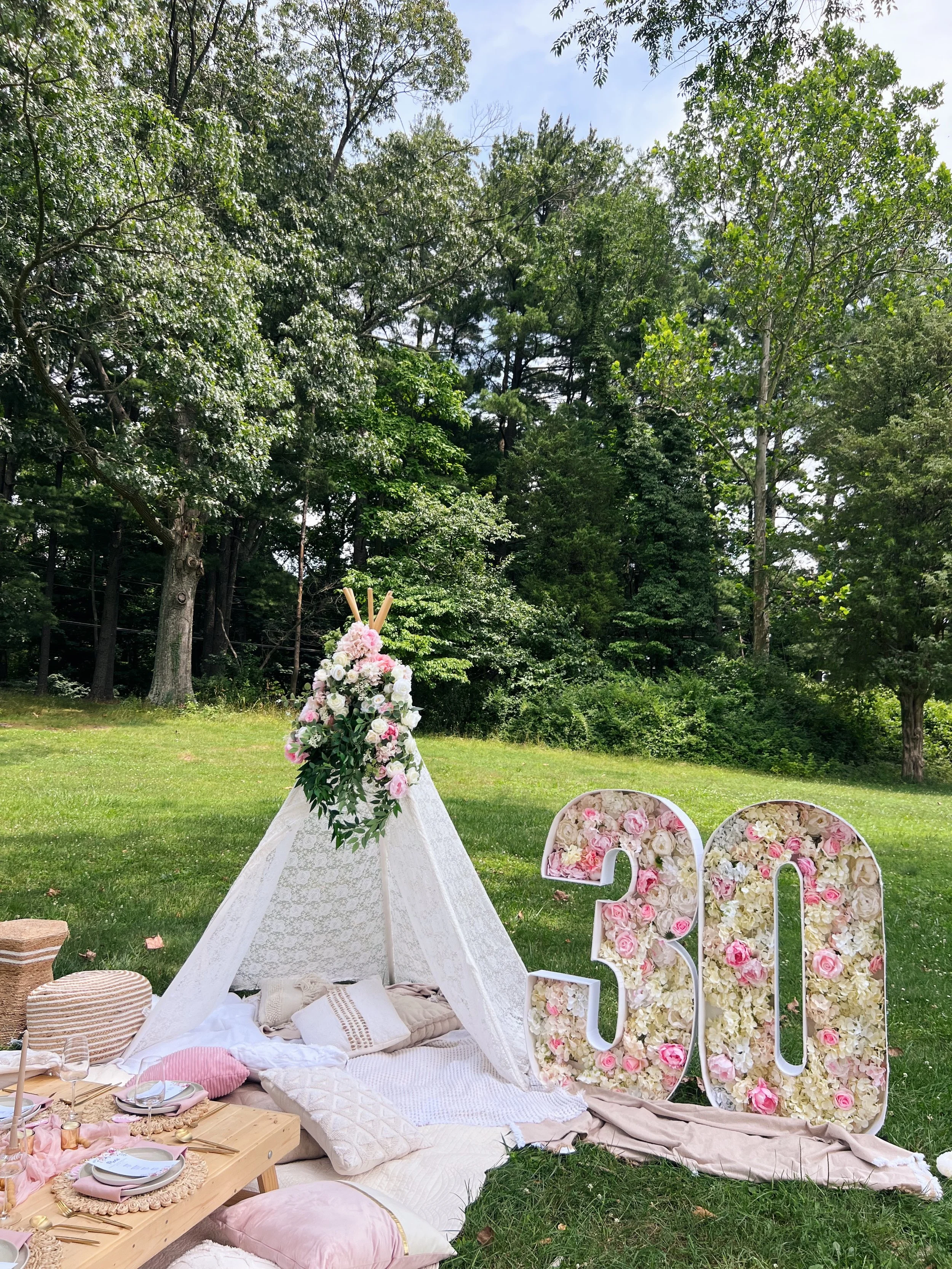Small cream colored teepee by outdoor picnic spread designed by Picnics By Peace