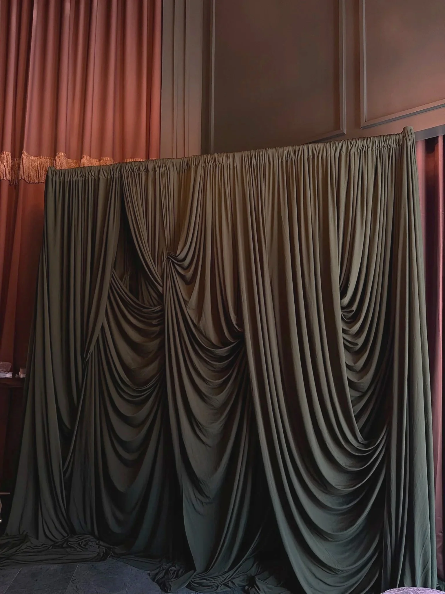 A display of elegantly draped curtains hanging from a wall in a room with pink and beige colors.