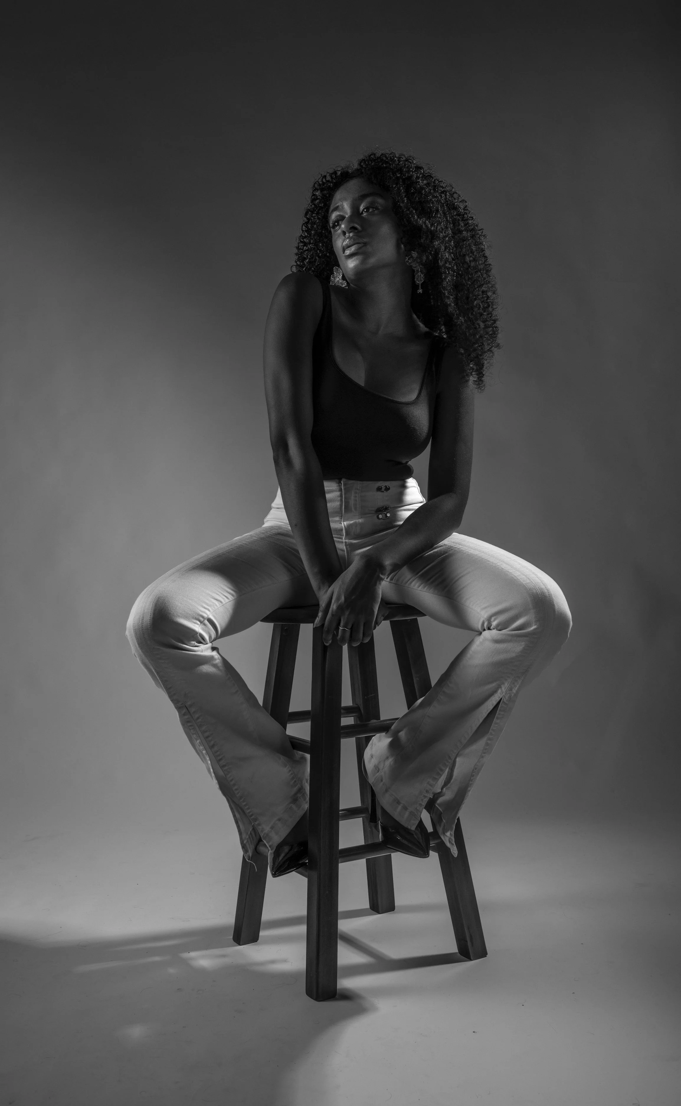 Model Amanda Whyte posing on a stool in a black and white spread for a magazine.