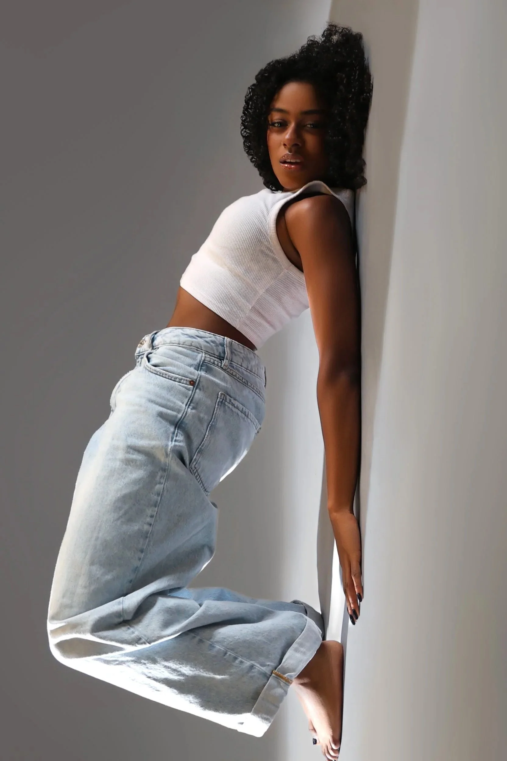 Canadian stuntwoman and actress, Amanda Whyte poses in a white tank and jeans in a studio session.
