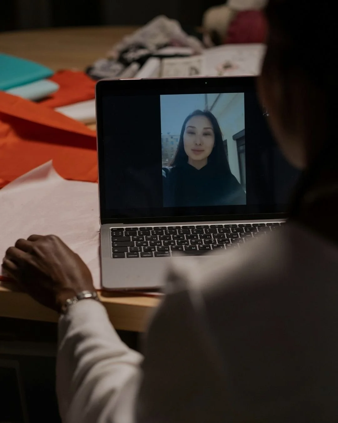 Person using a laptop for a video call, with an image of a young woman on the screen.