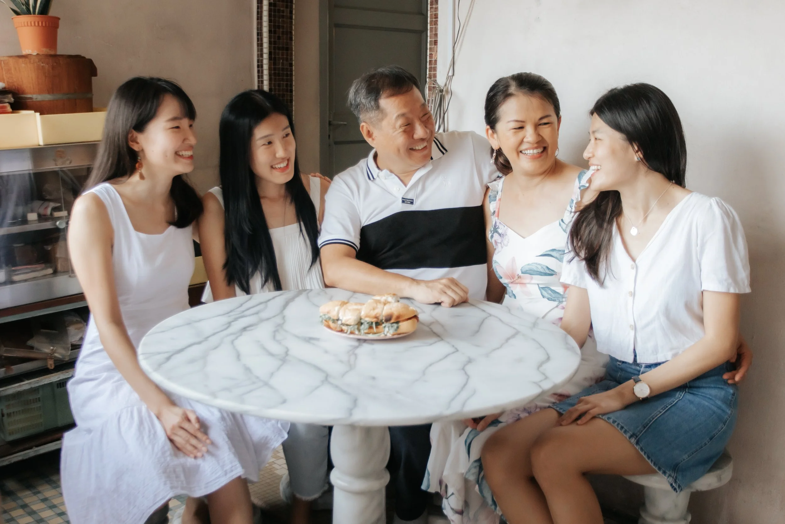 Heartwarming family photoshoot in Singapore featuring a family seated around a dinner table, captured in a light and airy style by Arielle for Breadandbutterworks.