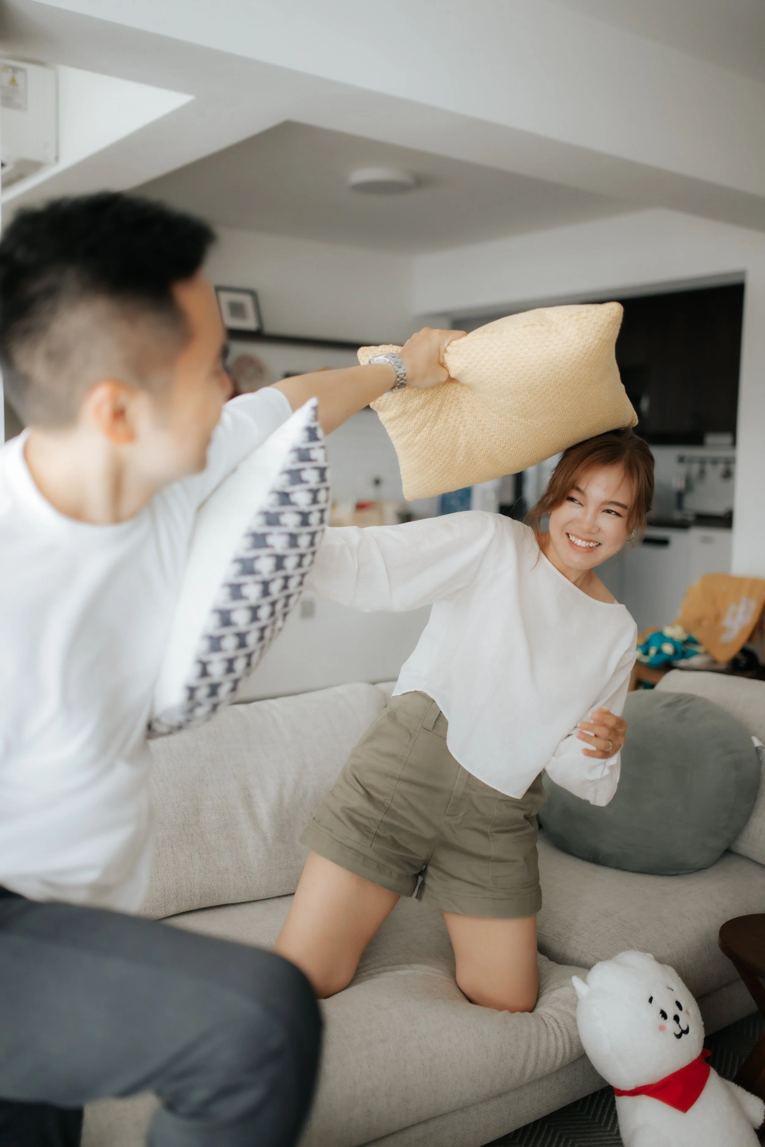 Light and airy pre-wedding photoshoot at a new marital BTO home of the couple having a pillow fight, captured by Ash for Breadandbutterworks.