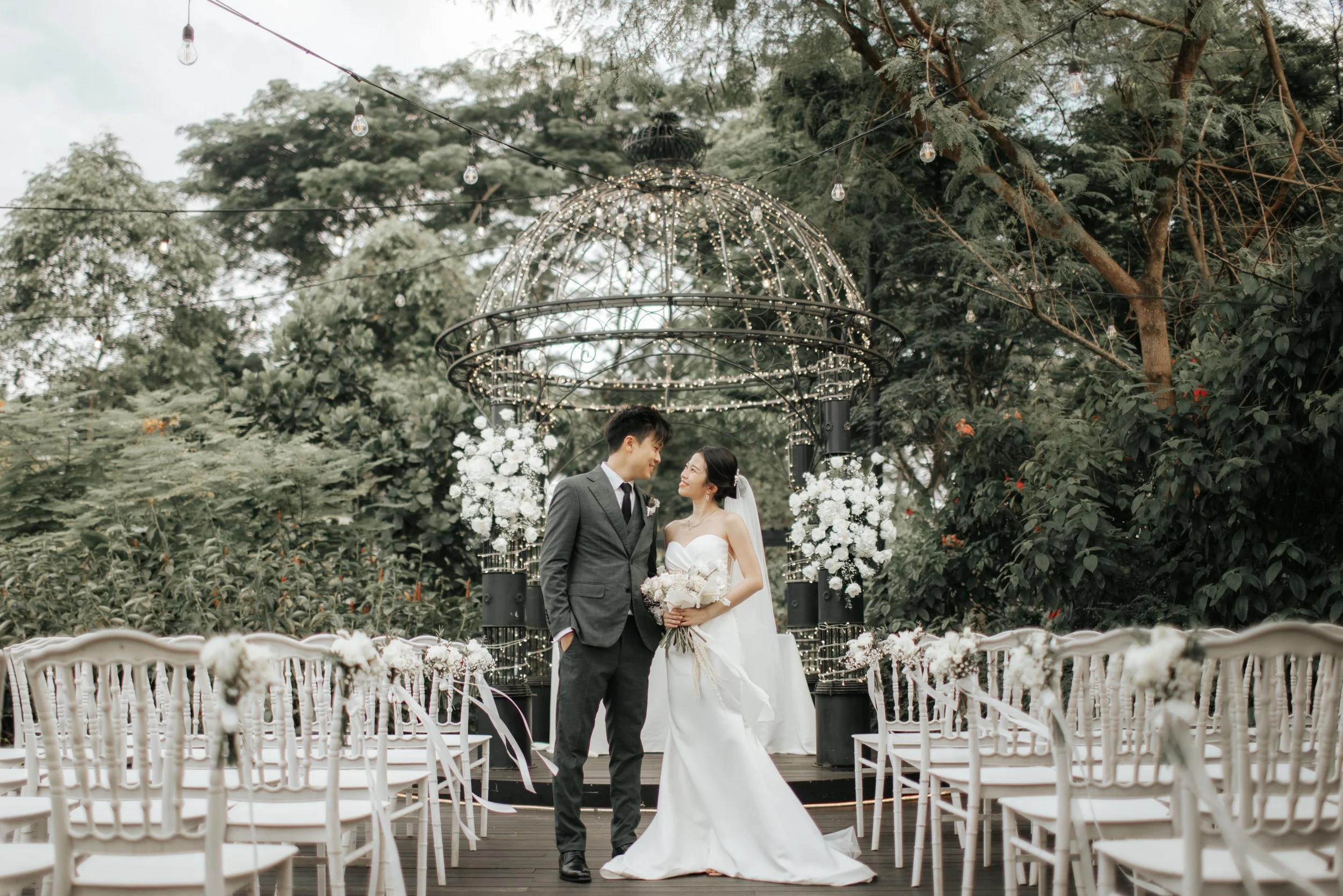 Light and airy actual day wedding photoshoot at the Summerhouse in Singapore of the couple posing in front of a gezabo. Captured by Arielle for Breadandbutterworks.