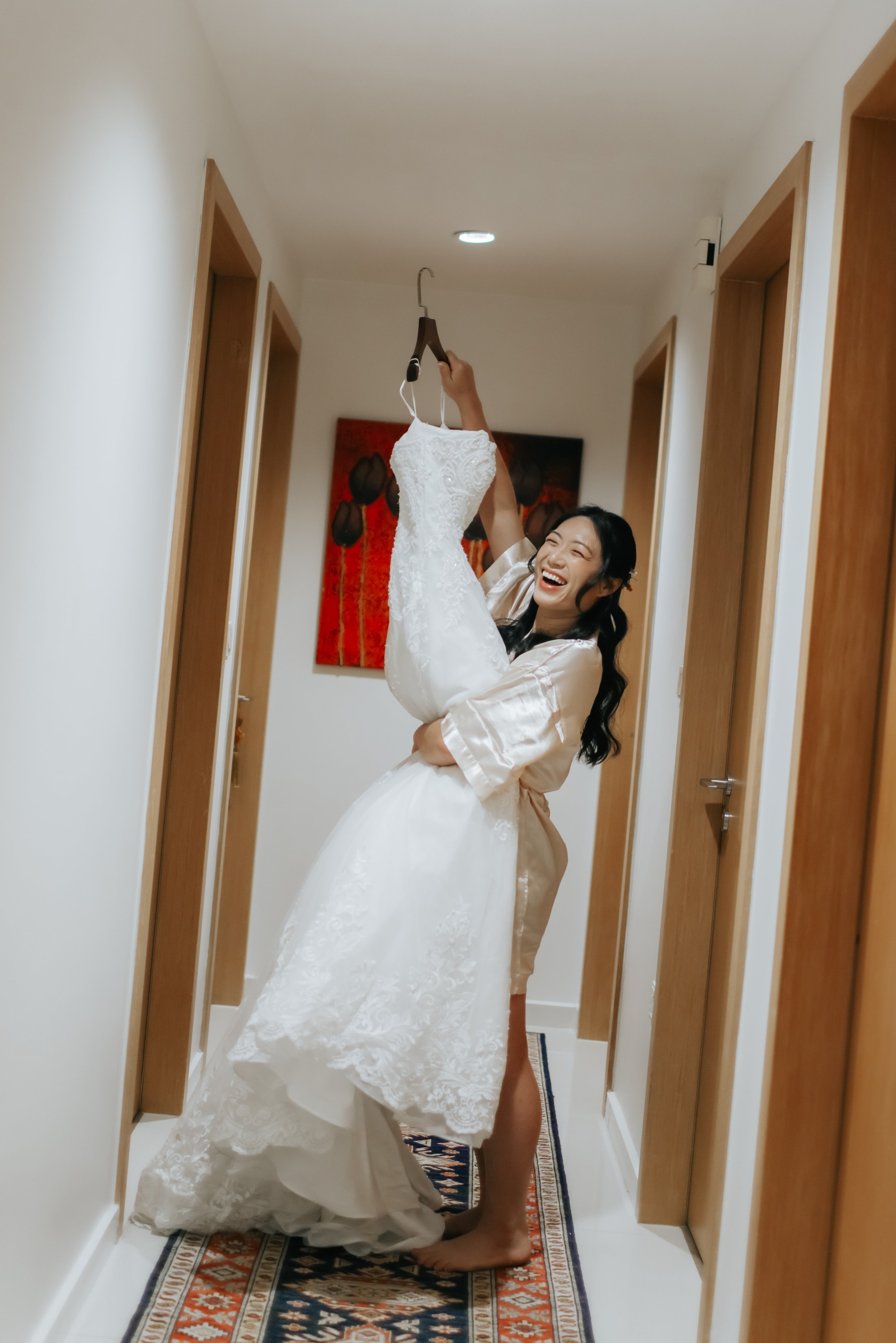 Actual day wedding photography of the bride-to-be excitedly looking at her wedding gown at home. Captured in a light and airy style by Arielle for Breadandbutterworks.
