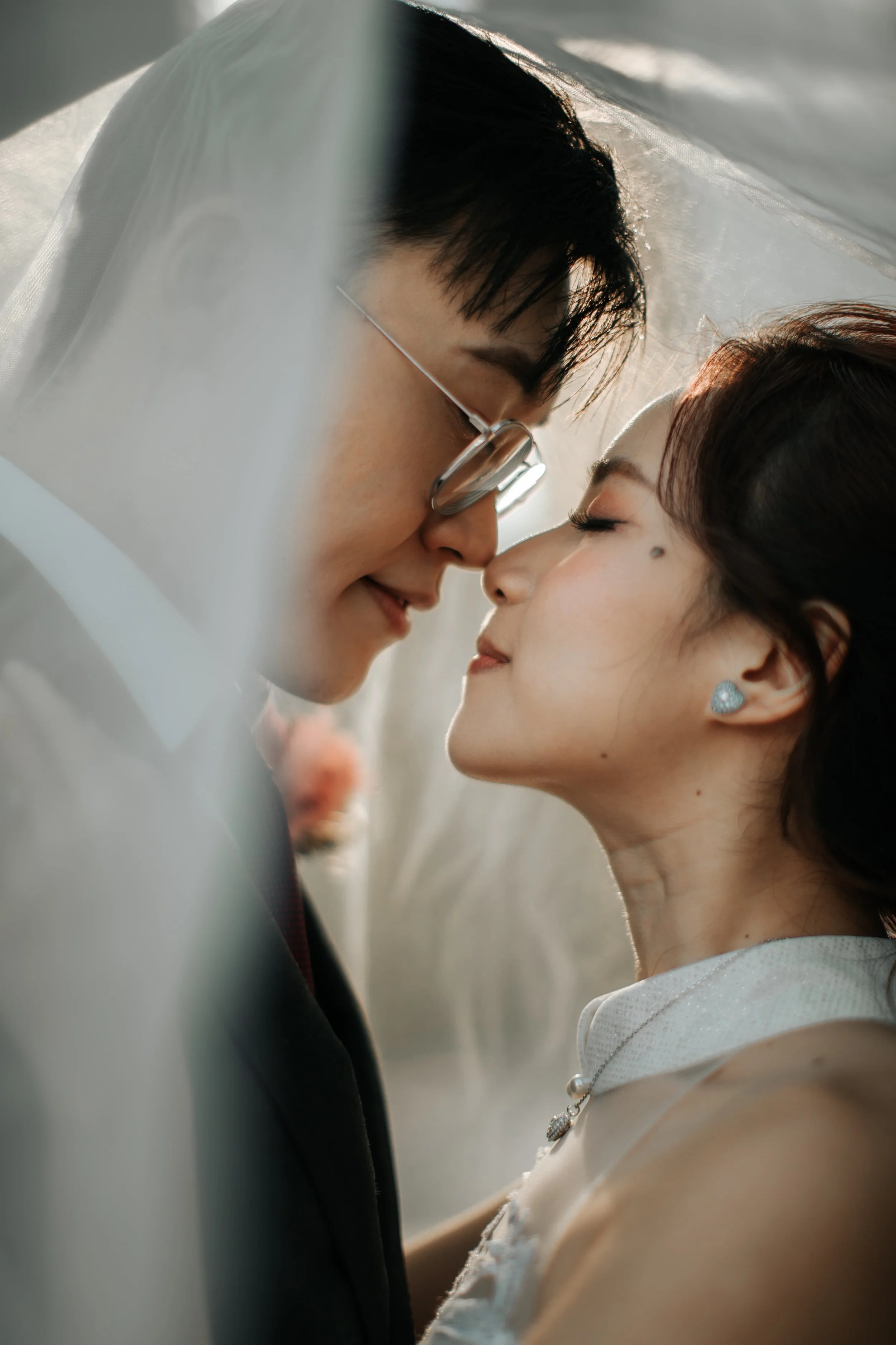 Light and airy actual day wedding photography of the bride and groom sharing a romantic moment beneath the bride's veil. Captured by Arielle for Breadandbutterworks.