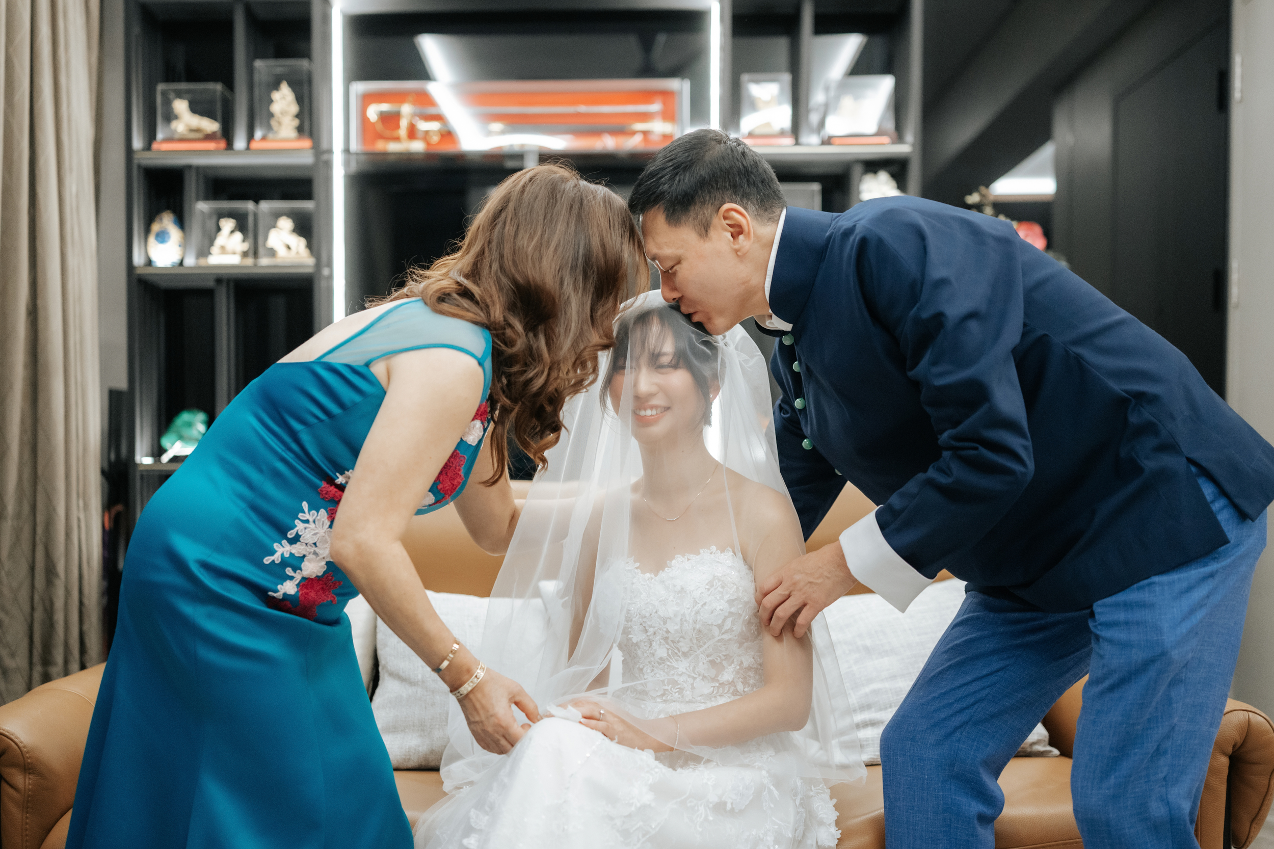 The bride-to-be spends a heartfelt moment with her parents as they finish veiling her and kiss her. Photographed by Breadandbutterworks.