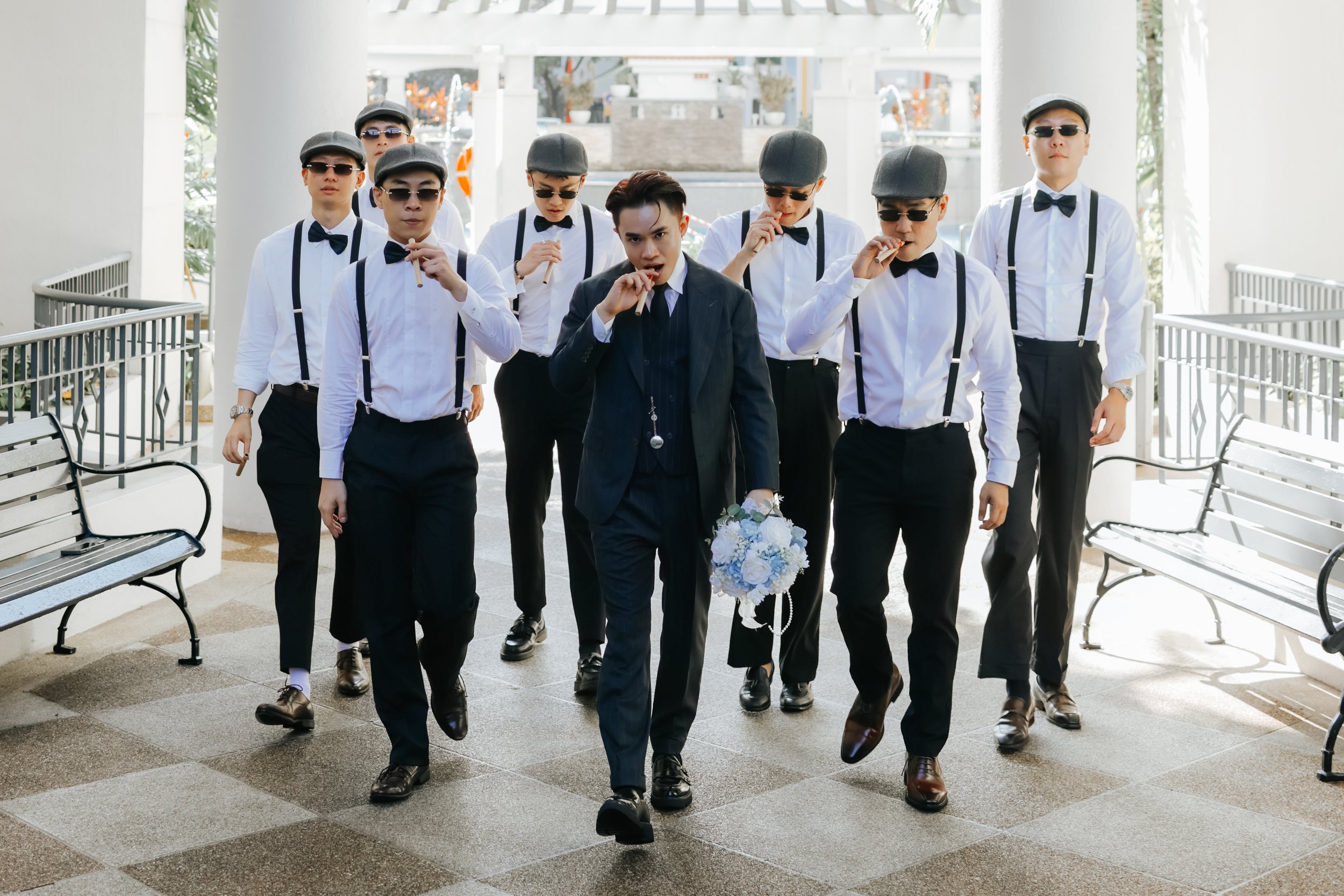 Light and airy actual day wedding photoshoot of the groom and the groomsmen. They are walking to the bride's home mimicking a scene from a period gangster drama, looking very cool and cinematic. Captured by Arielle from Breadandbutterworks.