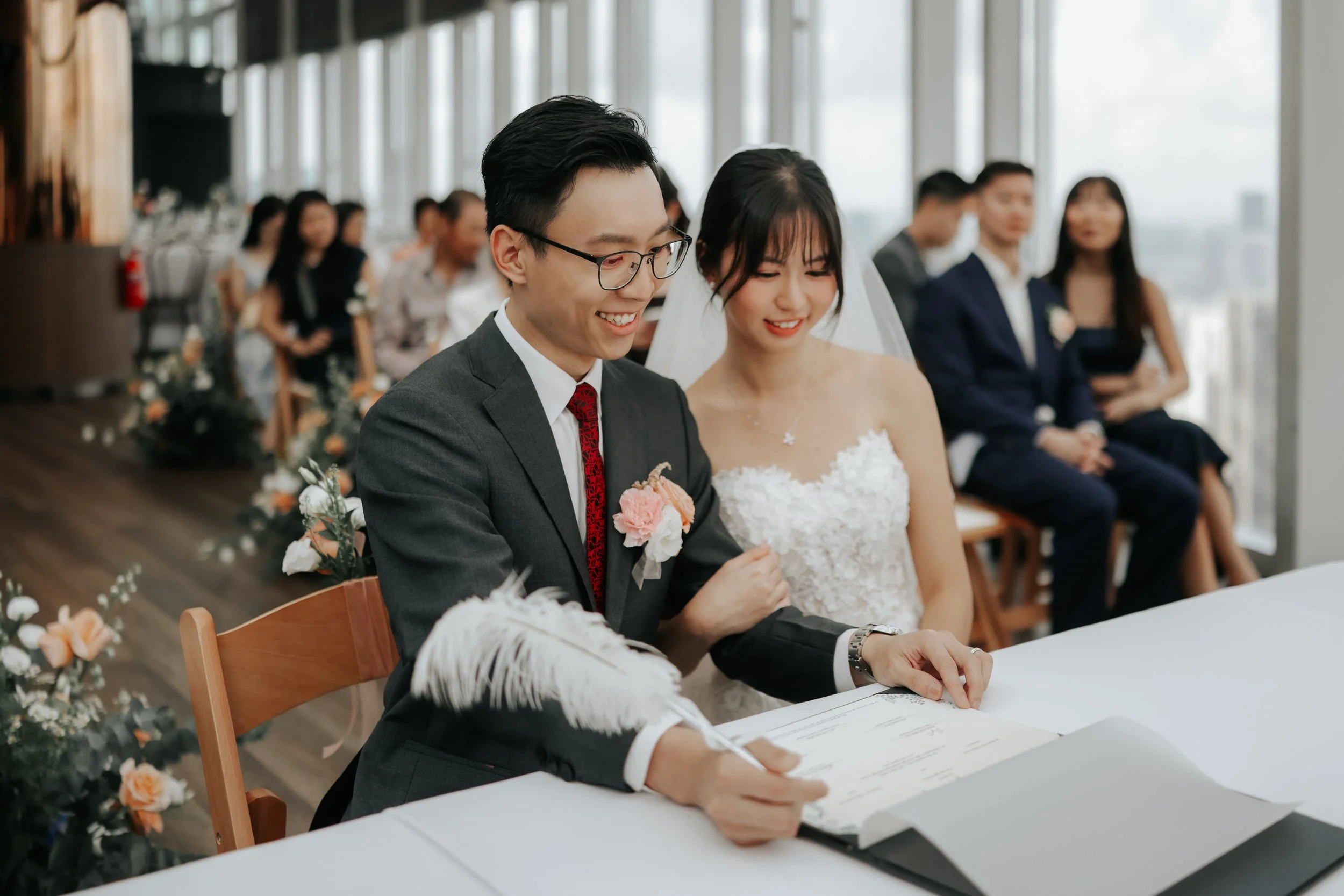 Romantic photograph of a couple signing their marriage papers while their beloved guests witness them. Photographed by Breadandbutterworks.