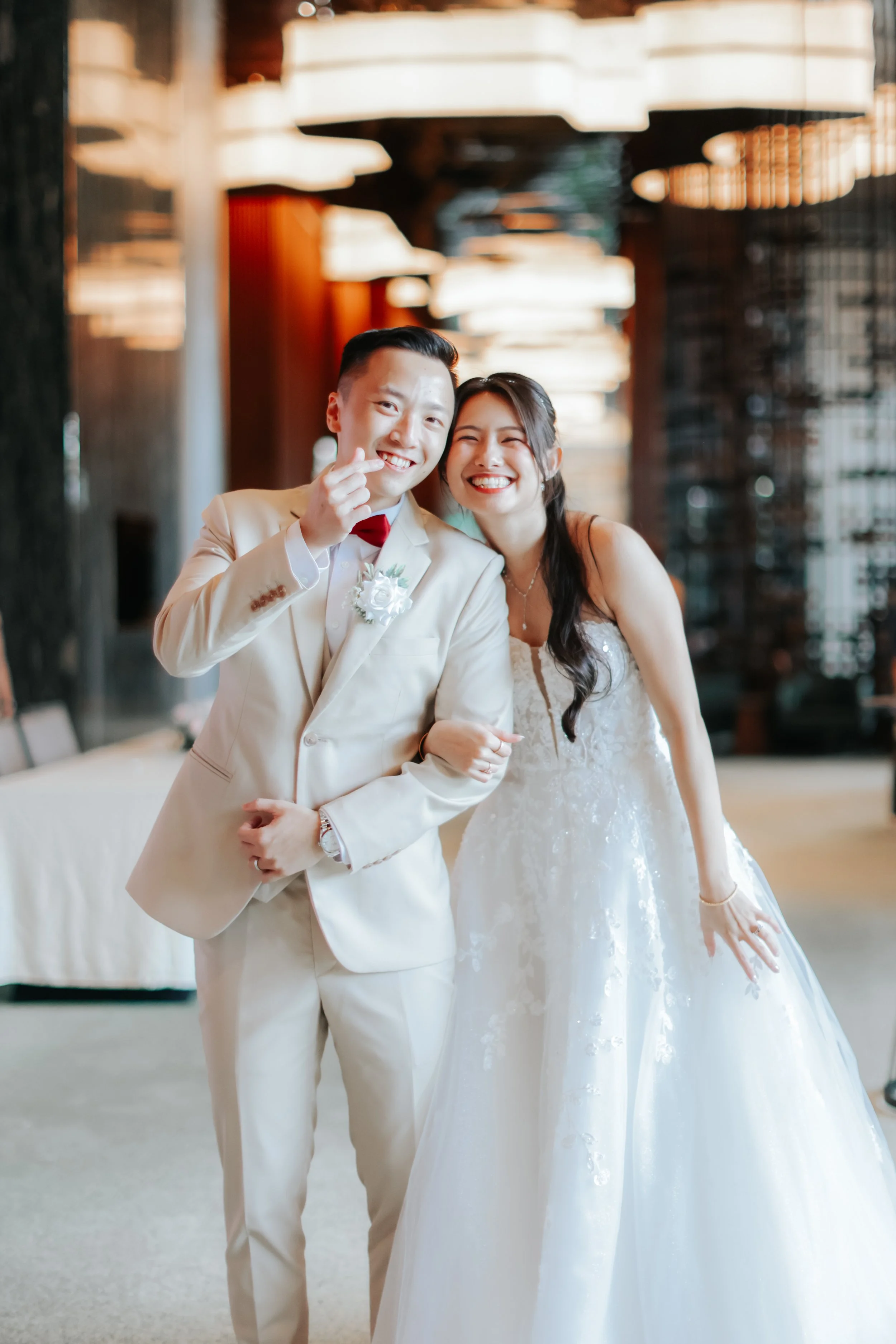 Joyful actual day wedding photography of the couple posing before marching into their wedding, captured by Breadandbutterworks in a soft and heartfelt style.
