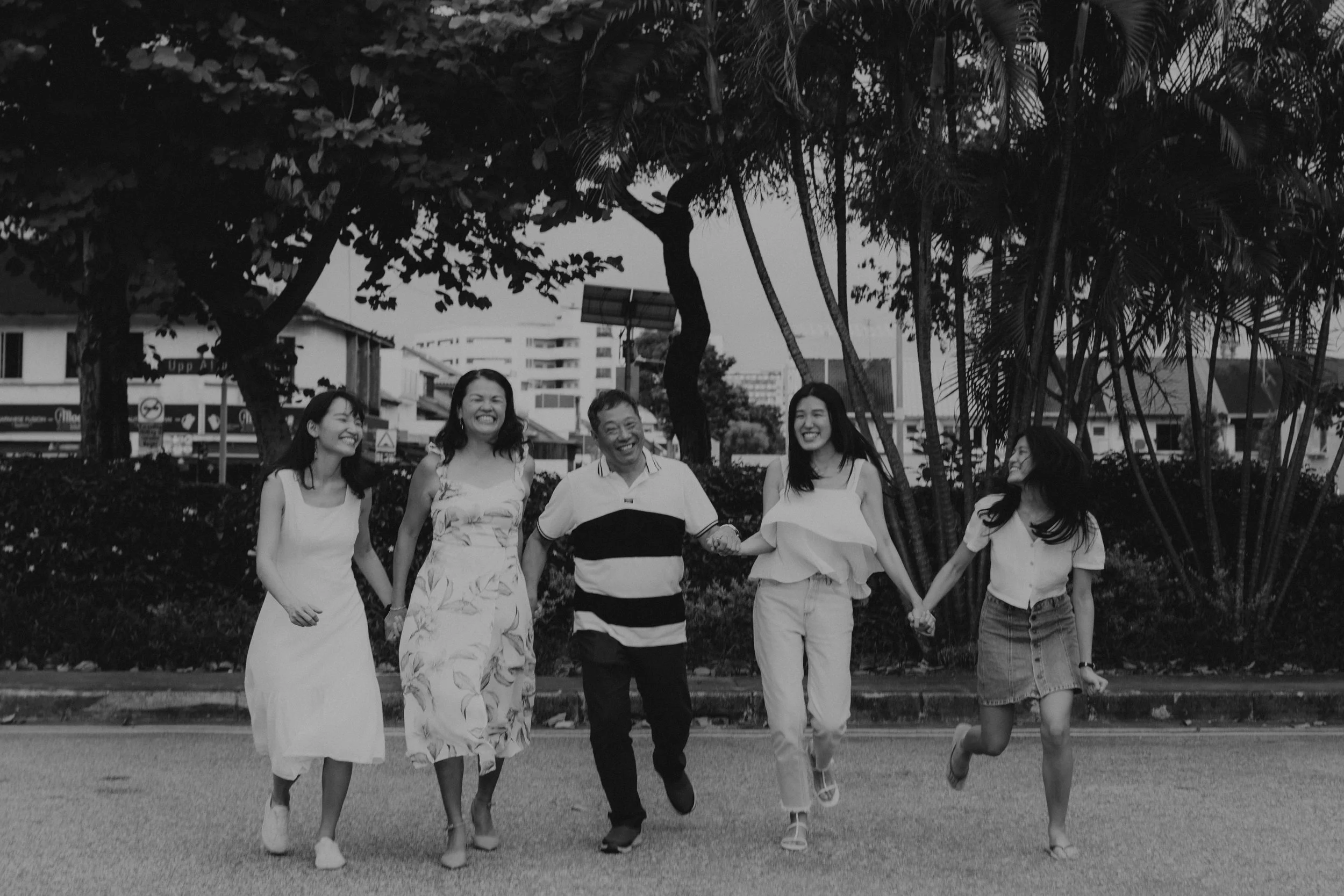 Heartwarming family photoshoot in Singapore featuring a family posing by the road, captured in a cinematic black and white style by Arielle for Breadandbutterworks.