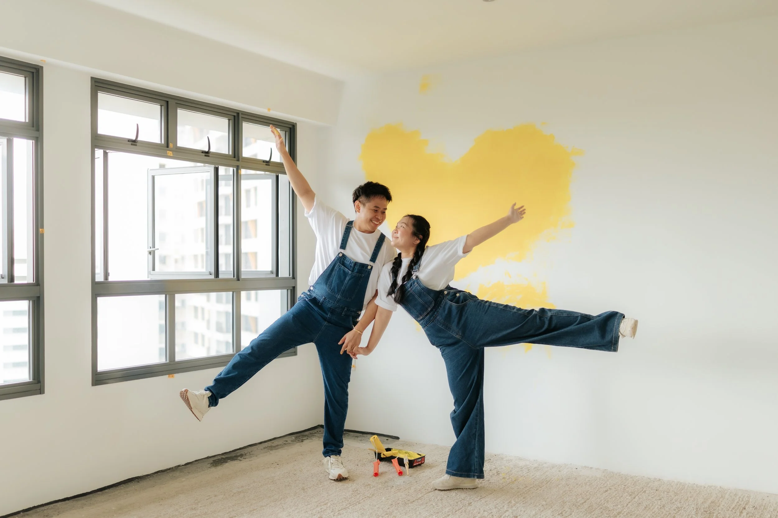 Playful home pre-wedding photo of a couple painting their marital home together, captured by Breadandbutterworks in a light, airy and heartfelt style.