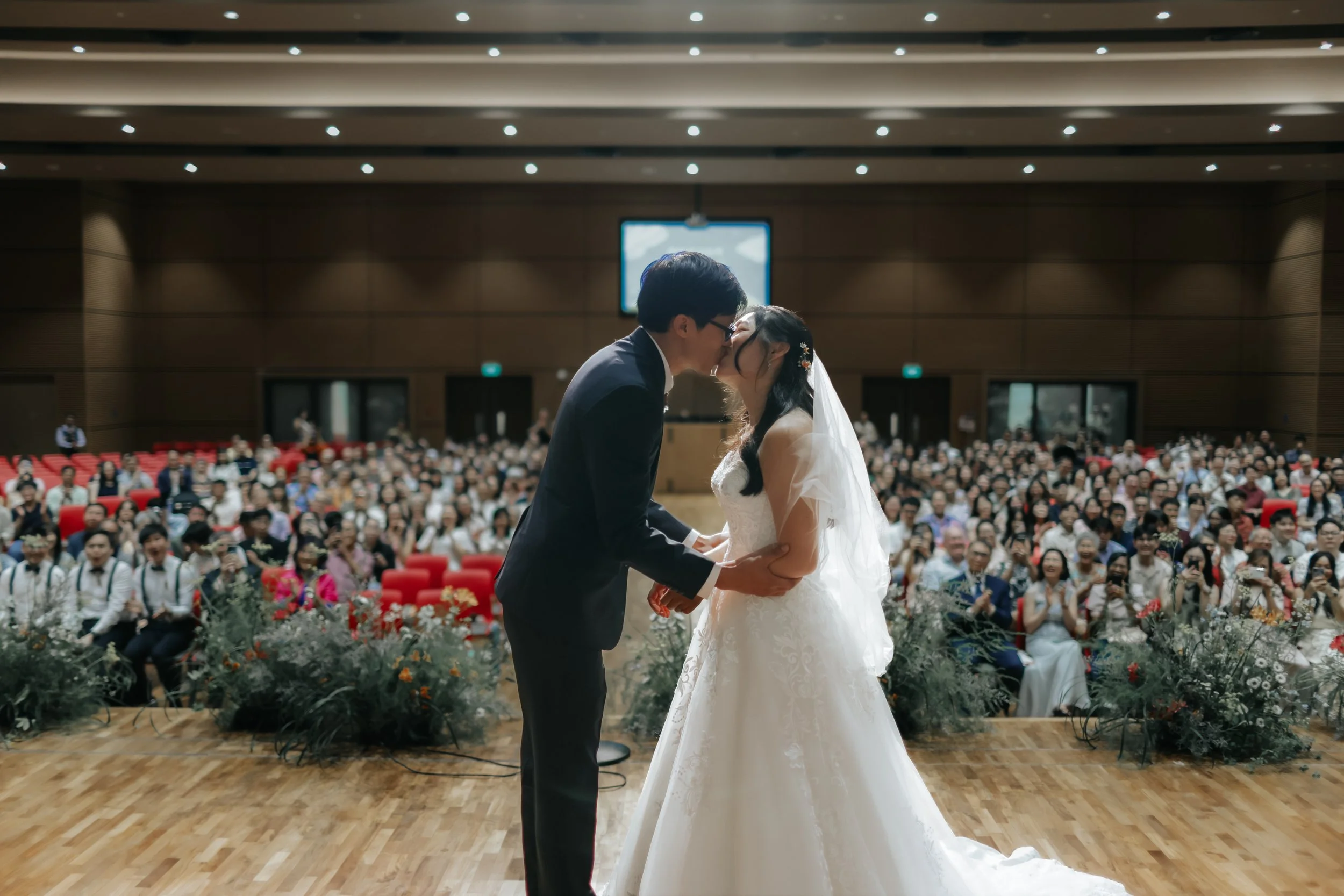 Actual day wedding shoot of the bride and groom at Adam Road Presbyterian Church in Singapore, they share a kiss after being pronounced husband and wife in front of their guests. Captured in a light and airy style by Arielle for Breadandbutterworks.