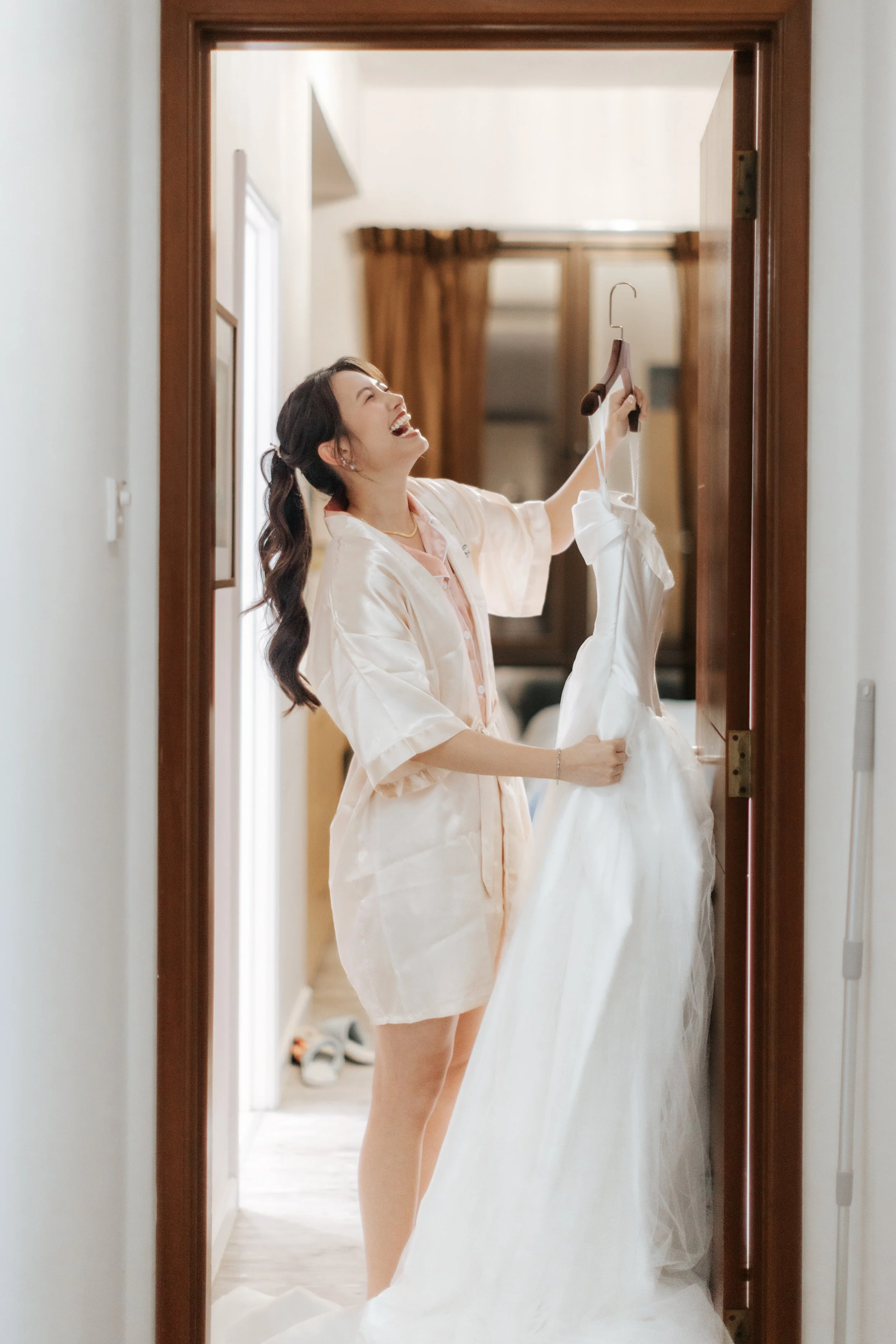 Joyful actual day wedding photography of the bride-to-be getting her wedding gown ready, captured by Breadandbutterworks in a soft and heartfelt style.