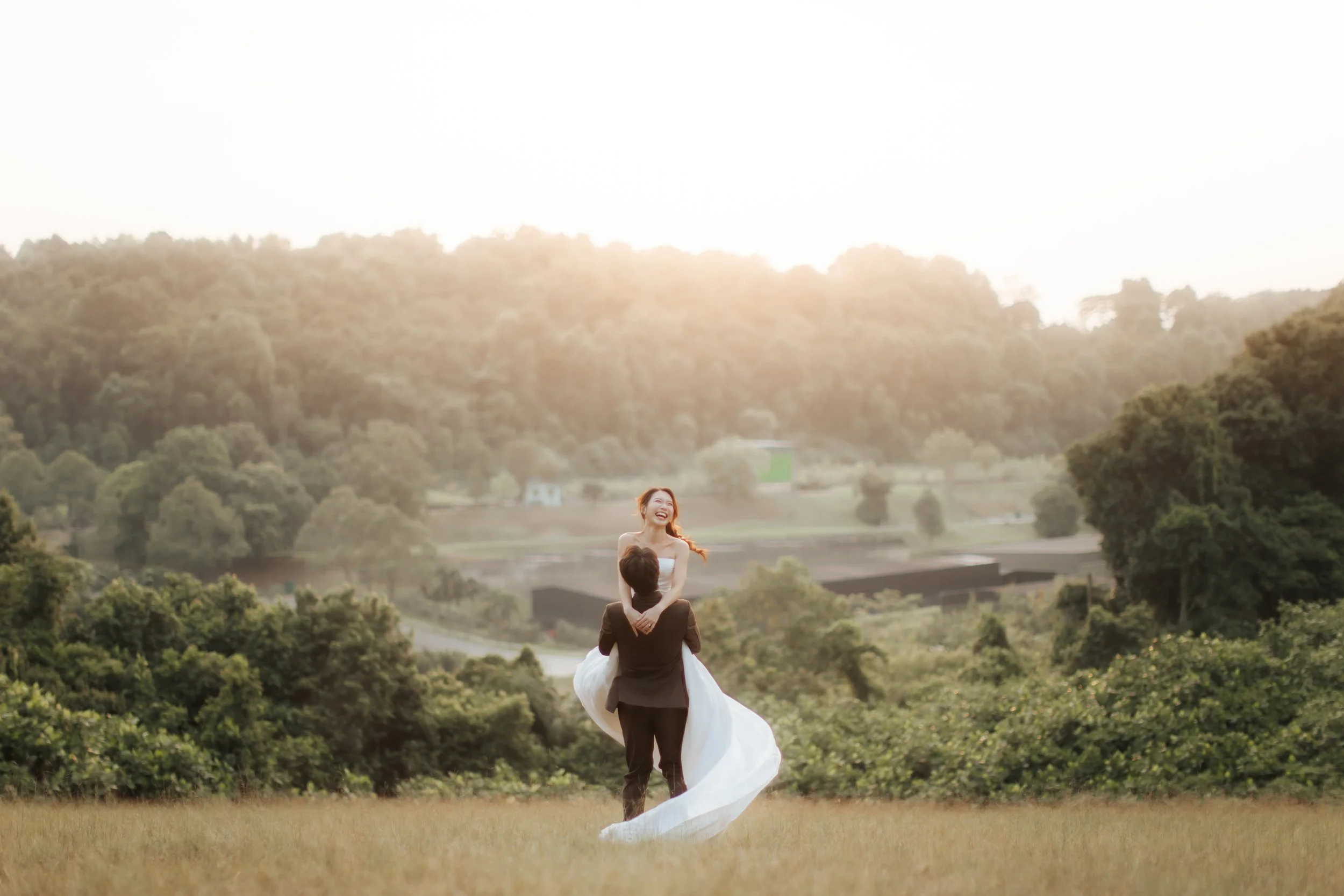 Romantic and dynamic pre-wedding photoshoot at Canterbury Hill. The groom is lifting up the bride and twirling her around as her gown trails behind gracefully. Captured in a light and airy style by Arielle from Breadandbutterworks.